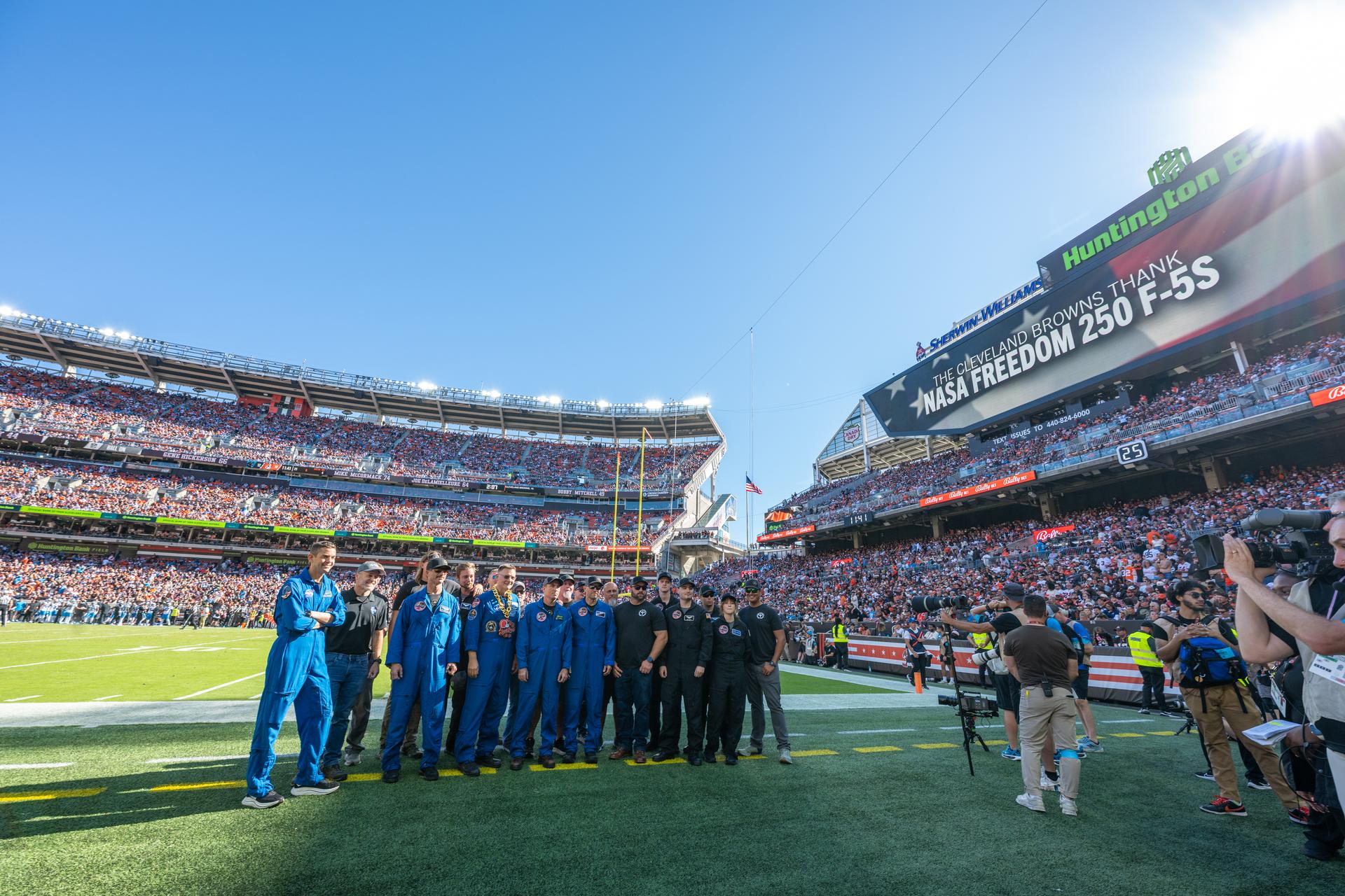 NASA Administrator Jared Isaacman and his Freedom 250 F-5 team (Jerry "Jive" Kerby, Doug "Tut" Demko and other members) along with NASA Astronaut Douglas Wheelock and Associate Administrator, Research and Technology Mission Directorate Dr. James Kenyon wave to fans on the field at an NFL game between the Cleveland Browns and the Carolina Panthers at Huntington Bank Field, Sunday, September 27th, 2026, in Cleveland, Ohio. NASA’s engagement at NFL games is part of the agency’s Inspiration Tour, aimed at strengthening connections between NASA and its partners and showcasing innovation in air and space in the lead up to the MAX POWER aerospace technology expo and airshow at the agency’s Kennedy Space Center in early November. Photo Credit: (NASA/Jordan Cochran)
