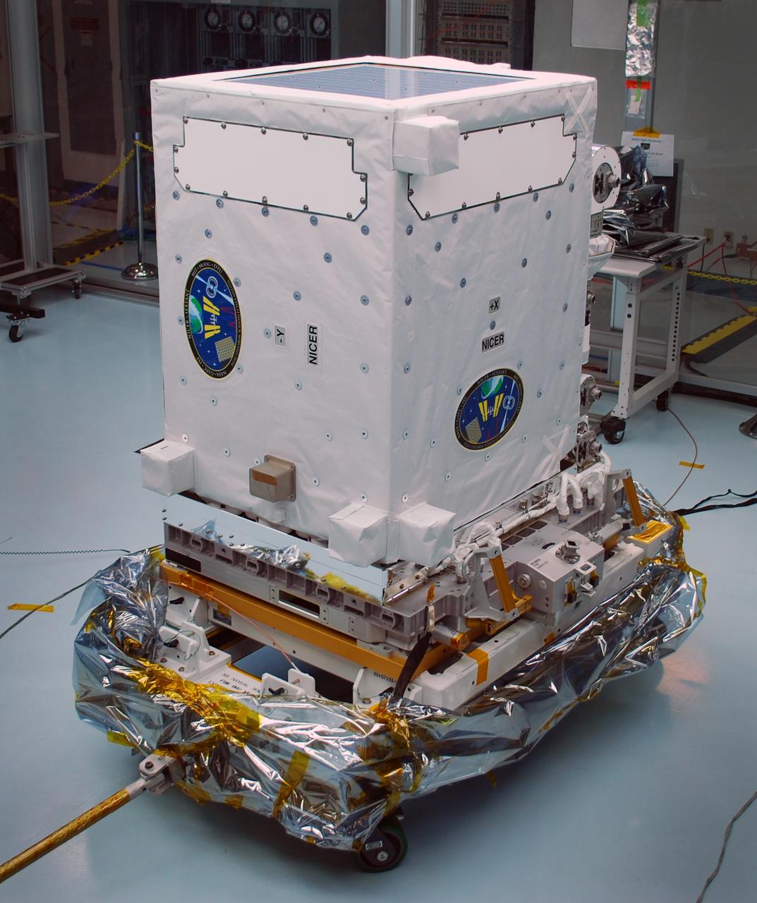 The NICER payload, blanketed and waiting for launch in the Space Station Processing Facility at NASA’s Kennedy Space Center in Cape Canaveral, Florida. The instrument is in its stowed configuration for launch. The Neutron star Interior Composition Explorer (NICER) is a NASA Explorer Mission of Opportunity dedicated to studying the extraordinary environments — strong gravity, ultra-dense matter, and the most powerful magnetic fields in the universe — embodied by neutron stars. An attached payload aboard the International Space Station, NICER will deploy an instrument with unique capabilities for timing and spectroscopy of fast X-ray brightness fluctuations. The embedded Station Explorer for X-ray Timing and Navigation Technology demonstration (SEXTANT) will use NICER data to validate, for the first time in space, technology that exploits pulsars as natural navigation beacons. Credit: NASA/Goddard/ Keith Gendreau <b><a href="http://www.nasa.gov/audience/formedia/features/MP_Photo_Guidelines.html" rel="nofollow">NASA image use policy.</a></b> <b><a href="http://www.nasa.gov/centers/goddard/home/index.html" rel="nofollow">NASA Goddard Space Flight Center</a></b> enables NASA’s mission through four scientific endeavors: Earth Science, Heliophysics, Solar System Exploration, and Astrophysics. Goddard plays a leading role in NASA’s accomplishments by contributing compelling scientific knowledge to advance the Agency’s mission. <b>Follow us on <a href="http://twitter.com/NASAGoddardPix" rel="nofollow">Twitter</a></b> <b>Like us on <a href="http://www.facebook.com/pages/Greenbelt-MD/NASA-Goddard/395013845897?ref=tsd" rel="nofollow">Facebook</a></b> <b>Find us on <a href="http://instagrid.me/nasagoddard/?vm=grid" rel="nofollow">Instagram</a></b>