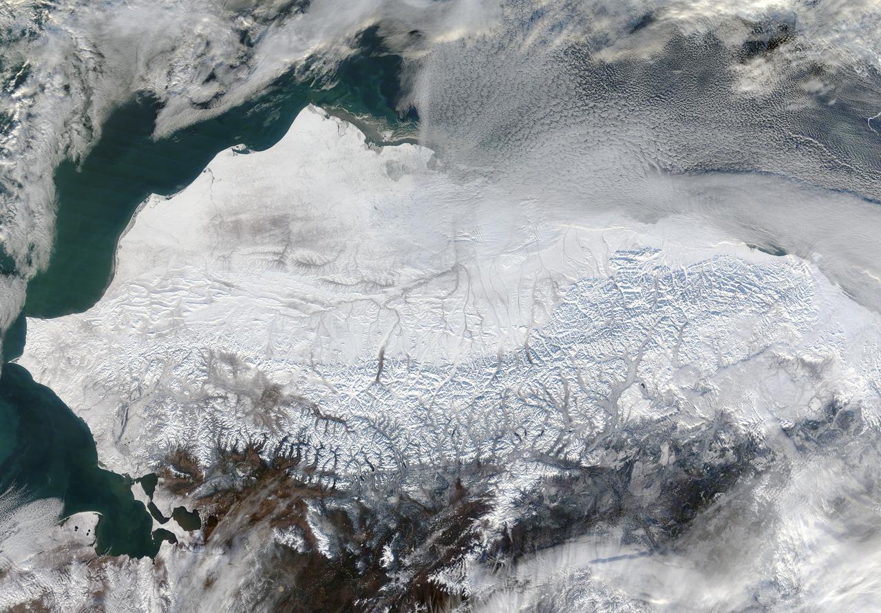 As autumn colors moved across much of the lower forty-eight states in mid-October 2015, winter weather had already arrived in Alaska. The Moderate Resolution Imaging Spectroradiometer (MODIS) aboard NASA’s Terra satellite captured this true-color image of the icy scene on October 16 as it passed over the region. Point Barrow, the northern-most location in the United States sits between the Chukchi Sea (west) and the Beaufort Sea on the east. The rugged peaks of the Brooks Range can be seen along the southern section of the image. North of the Brooks Range the land is almost entirely covered with snow; to the south the tan and browns visible between snow marks uncovered land. Sea ice lies over the waters near the coasts of much of Alaska’s North Slope, especially east of Point Barrow. White cloud banks are notable in the northeast and southeast sections of the image. Credit: NASA/GSFC/Jeff Schmaltz/MODIS Land Rapid Response Team <b><a href="http://www.nasa.gov/audience/formedia/features/MP_Photo_Guidelines.html" rel="nofollow">NASA image use policy.</a></b> <b><a href="http://www.nasa.gov/centers/goddard/home/index.html" rel="nofollow">NASA Goddard Space Flight Center</a></b> enables NASA’s mission through four scientific endeavors: Earth Science, Heliophysics, Solar System Exploration, and Astrophysics. Goddard plays a leading role in NASA’s accomplishments by contributing compelling scientific knowledge to advance the Agency’s mission. <b>Follow us on <a href="http://twitter.com/NASAGoddardPix" rel="nofollow">Twitter</a></b> <b>Like us on <a href="http://www.facebook.com/pages/Greenbelt-MD/NASA-Goddard/395013845897?ref=tsd" rel="nofollow">Facebook</a></b> <b>Find us on <a href="http://instagrid.me/nasagoddard/?vm=grid" rel="nofollow">Instagram</a></b>