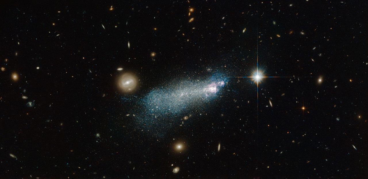 The bright streak of glowing gas and stars in this NASA/ESA Hubble Space Telescope image is known as PGC 51017, or SBSG 1415+437. It is a type of galaxy known as a blue compact dwarf.  This particular dwarf is well studied and has an interesting star formation history. Astronomers initially thought that SBS 1415+437 was a very young galaxy currently undergoing its very first burst of star formation, but more recent studies have suggested that the galaxy is in fact a little older, containing stars over 1.3 billion years old.  Starbursts are an area of ongoing research for astronomers — short-lived and intense periods of star formation, during which huge amounts of gas within a galaxy are hungrily used up to form newborn stars.   Read more: <a href="http://1.usa.gov/1ExsNx0" rel="nofollow">1.usa.gov/1ExsNx0</a> Credit: ESA/Hubble and NASA  Acknowledgement: Alessandra Aloisi (STScI) and Nick Rose  <b><a href="http://www.nasa.gov/audience/formedia/features/MP_Photo_Guidelines.html" rel="nofollow">NASA image use policy.</a></b>  <b><a href="http://www.nasa.gov/centers/goddard/home/index.html" rel="nofollow">NASA Goddard Space Flight Center</a></b> enables NASA’s mission through four scientific endeavors: Earth Science, Heliophysics, Solar System Exploration, and Astrophysics. Goddard plays a leading role in NASA’s accomplishments by contributing compelling scientific knowledge to advance the Agency’s mission.  <b>Follow us on <a href="http://twitter.com/NASAGoddardPix" rel="nofollow">Twitter</a></b>  <b>Like us on <a href="http://www.facebook.com/pages/Greenbelt-MD/NASA-Goddard/395013845897?ref=tsd" rel="nofollow">Facebook</a></b>  <b>Find us on <a href="http://instagrid.me/nasagoddard/?vm=grid" rel="nofollow">Instagram</a></b>