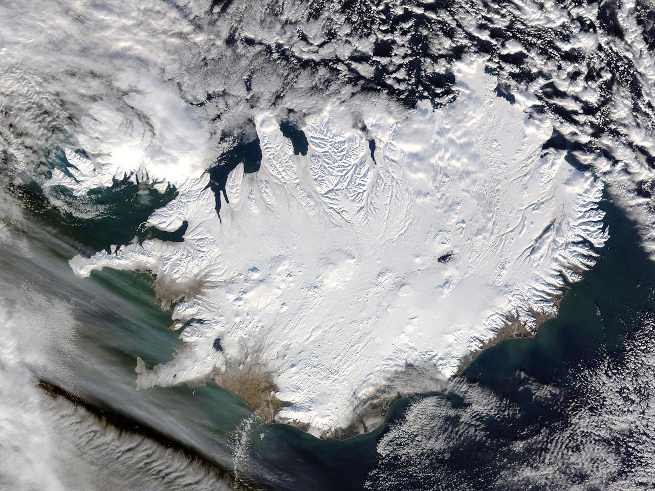 Iceland, dressed in winter white, peaked through a hole in a complex system of clouds in late February, 2015. The Moderate Resolution Imaging Spectroradiometer (MODIS) aboard NASA’s Terra satellite captured this true-color image on February 21 as it passed over the region. Ice and snow covers Iceland almost entirely, except for coastal regions in the southwest and southeast. The extensive, roughly H-shaped area in the southeast section of the island is Vatnajökull, Iceland’s largest glacier. Hidden underneath the ice lies Bardarbunga, a large subglacial stratovolcano. On August 31, 2014 the volcano began an eruption at two fissures to the north of the glacier and deposited a lava field that measured about 131 feet (40 meters) at its thickest points, and covered an area about 33 sq. mi (85 sq. km) by the time the eruption ended on February 27, 2015. The massive lava flow left its mark on Iceland – the cooled lava can be seen as the roughly oval black area to the north of the Vatnajökull glacier. Credit: NASA/GSFC/Jeff Schmaltz/MODIS Land Rapid Response Team <b><a href="http://www.nasa.gov/audience/formedia/features/MP_Photo_Guidelines.html" rel="nofollow">NASA image use policy.</a></b> <b><a href="http://www.nasa.gov/centers/goddard/home/index.html" rel="nofollow">NASA Goddard Space Flight Center</a></b> enables NASA’s mission through four scientific endeavors: Earth Science, Heliophysics, Solar System Exploration, and Astrophysics. Goddard plays a leading role in NASA’s accomplishments by contributing compelling scientific knowledge to advance the Agency’s mission. <b>Follow us on <a href="http://twitter.com/NASAGoddardPix" rel="nofollow">Twitter</a></b> <b>Like us on <a href="http://www.facebook.com/pages/Greenbelt-MD/NASA-Goddard/395013845897?ref=tsd" rel="nofollow">Facebook</a></b> <b>Find us on <a href="http://instagram.com/nasagoddard?vm=grid" rel="nofollow">Instagram</a></b>