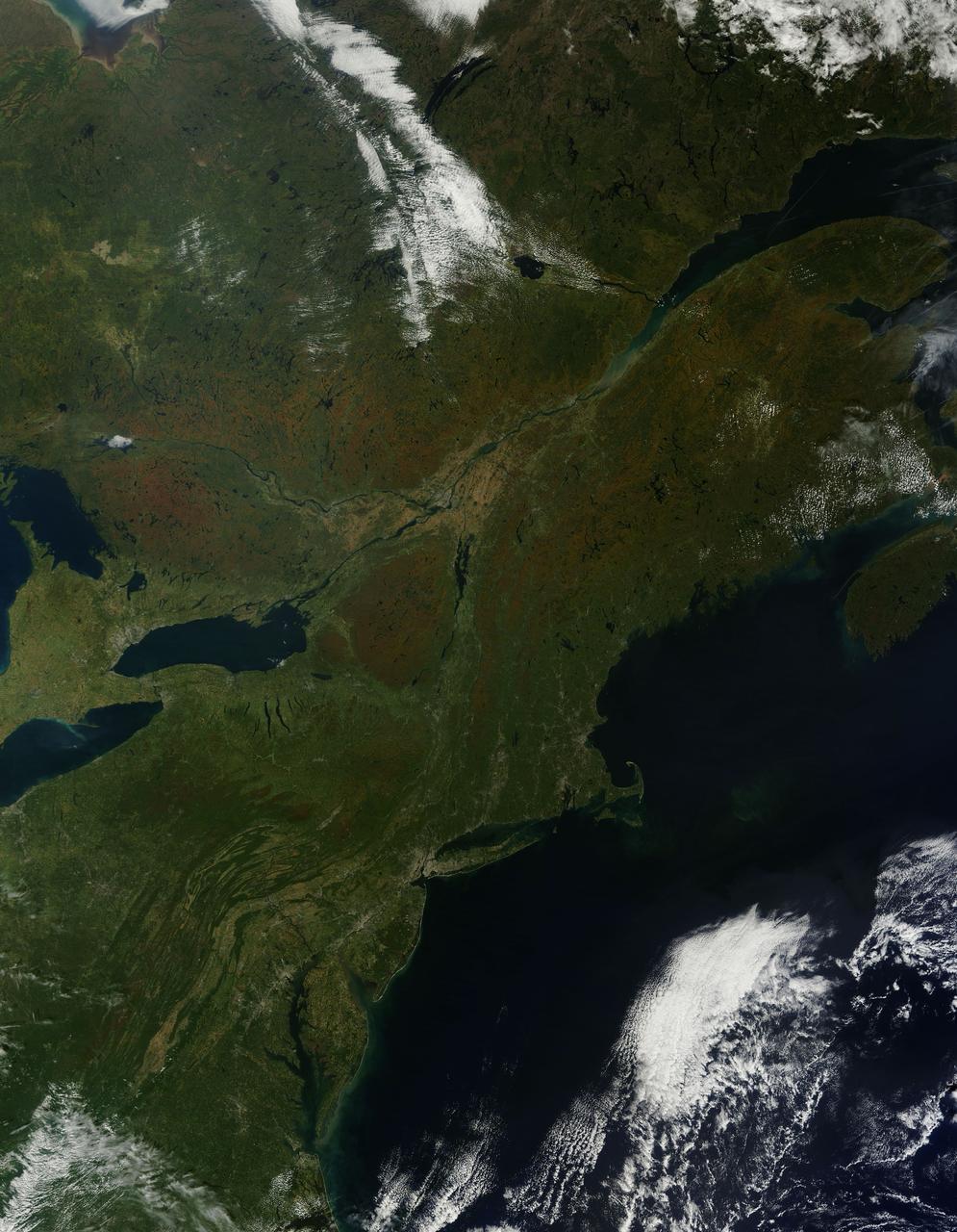 As temperatures dropped and daylight began to shorten, autumn colors began to wash over the deciduous forests of North America. The Moderate Resolution Imaging Spectroradiometer (MODIS) aboard NASA’s Terra satellite captured this true-color image of the northeastern United States and Canada on September 27, 2014. Washes of orange, brown and yellow are brightest in the Upper Peninsula of Michigan, upstate New York, New Hampshire, Vermont, Maine, and southern Quebec and Ontario. Also, faint traces of phytoplankton blooms can be seen in the offshore waters of the Atlantic Ocean. The transition of autumn leaves from green, to glowing with colors, to browning and dropping to the ground, involve several complex interactions and reactions. However, length of sunlight and the temperature changes are dominant factors. Topography also plays a role, as does latitude. Temperature tends to drop faster at higher elevations and at higher latitudes, and day length shortens more quickly at higher latitudes. Color change tends to begin in the north and sweep southward, and change begins at mountain tops then moves into valleys. As explained by the U.S. Forest Service, certain species of trees produce certain colors. Oaks generally turn red, brown, or russet; hickories become golden bronze; aspen and yellow-poplar turn golden. Maples differ by species. Red maple turns brilliant scarlet; sugar maple, orange-red; and black maple, yellow. Leaves of some trees, such as elms, simply become brown. Credit: NASA/GSFC/Jeff Schmaltz/MODIS Land Rapid Response Team <b><a href="http://www.nasa.gov/audience/formedia/features/MP_Photo_Guidelines.html" rel="nofollow">NASA image use policy.</a></b> <b><a href="http://www.nasa.gov/centers/goddard/home/index.html" rel="nofollow">NASA Goddard Space Flight Center</a></b> enables NASA’s mission through four scientific endeavors: Earth Science, Heliophysics, Solar System Exploration, and Astrophysics. Goddard plays a leading role in NASA’s accomplishments by contributing compelling scientific knowledge to advance the Agency’s mission. <b>Follow us on <a href="http://twitter.com/NASAGoddardPix" rel="nofollow">Twitter</a></b> <b>Like us on <a href="http://www.facebook.com/pages/Greenbelt-MD/NASA-Goddard/395013845897?ref=tsd" rel="nofollow">Facebook</a></b> <b>Find us on <a href="http://instagram.com/nasagoddard?vm=grid" rel="nofollow">Instagram</a></b>