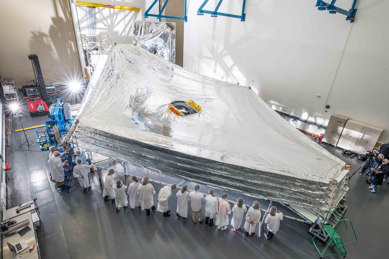 The Sunshield on NASA's James Webb Space Telescope is the largest part of the observatory—five layers of thin membrane that must unfurl reliably in space to precise tolerances. Last week, for the first time, engineers stacked and unfurled a full-sized test unit of the Sunshield and it worked perfectly. The Sunshield is about the length of a tennis court, and will be folded up like an umbrella around the Webb telescope’s mirrors and instruments during launch. Once it reaches its orbit, the Webb telescope will receive a command from Earth to unfold, and separate the Sunshield's five layers into their precisely stacked arrangement with its kite-like shape. The Sunshield test unit was stacked and expanded at a cleanroom in the Northrop Grumman facility in Redondo Beach, California. The Sunshield separates the observatory into a warm sun-facing side and a cold side where the sunshine is blocked from interfering with the sensitive infrared instruments. The infrared instruments need to be kept very cold (under 50 K or -370 degrees F) to operate. The Sunshield protects these sensitive instruments with an effective sun protection factor or SPF of 1,000,000 (suntan lotion generally has an SPF of 8-50). In addition to providing a cold environment, the Sunshield provides a thermally stable environment. This stability is essential to maintaining proper alignment of the primary mirror segments as the telescope changes its orientation to the sun. The James Webb Space Telescope is the successor to NASA's Hubble Space Telescope. It will be the most powerful space telescope ever built. Webb is an international project led by NASA with its partners, the European Space Agency and the Canadian Space Agency. For more information about the Webb telescope, visit: <a href="http://www.jwst.nasa.gov" rel="nofollow">www.jwst.nasa.gov</a> or <a href="http://www.nasa.gov/webb" rel="nofollow">www.nasa.gov/webb</a> For more information on the Webb Sunshield, visit: <a href="http://jwst.nasa.gov/sunshield.html" rel="nofollow">jwst.nasa.gov/sunshield.html</a> Credit: NASA/Goddard/Chris Gunn <b><a href="http://www.nasa.gov/audience/formedia/features/MP_Photo_Guidelines.html" rel="nofollow">NASA image use policy.</a></b> <b><a href="http://www.nasa.gov/centers/goddard/home/index.html" rel="nofollow">NASA Goddard Space Flight Center</a></b> enables NASA’s mission through four scientific endeavors: Earth Science, Heliophysics, Solar System Exploration, and Astrophysics. Goddard plays a leading role in NASA’s accomplishments by contributing compelling scientific knowledge to advance the Agency’s mission. <b>Follow us on <a href="http://twitter.com/NASAGoddardPix" rel="nofollow">Twitter</a></b> <b>Like us on <a href="http://www.facebook.com/pages/Greenbelt-MD/NASA-Goddard/395013845897?ref=tsd" rel="nofollow">Facebook</a></b> <b>Find us on <a href="http://instagram.com/nasagoddard?vm=grid" rel="nofollow">Instagram</a></b>