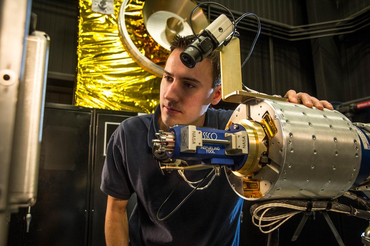 RROxiTT lead roboticist Alex Janas stands with the Oxidizer Nozzle Tool as he examines the work site.  Credit: NASA/Goddard/Chris Gunn  NASA has successfully concluded a remotely controlled test of new technologies that would empower future space robots to transfer hazardous oxidizer – a type of propellant – into the tanks of satellites in space today.    Concurrently on the ground, NASA is incorporating results from this test and the Robotic Refueling Mission on the International Space Station to prepare for an upcoming ground-based test of a full-sized robotic servicer system that will perform tasks on a mock satellite client.    Collectively, these efforts are part of an ongoing and aggressive technology development campaign to equip robots and humans with the tools and capabilities needed for spacecraft maintenance and repair, the assembly of large space telescopes, and extended human exploration.  Read more here: <a href="http://www.nasa.gov/content/goddard/nasa-tests-new-robotic-refueling-technologies/#.UxeLyyRkLH4" rel="nofollow">www.nasa.gov/content/goddard/nasa-tests-new-robotic-refue...</a>  <b><a href="http://www.nasa.gov/audience/formedia/features/MP_Photo_Guidelines.html" rel="nofollow">NASA image use policy.</a></b>   <b><a href="http://www.nasa.gov/centers/goddard/home/index.html" rel="nofollow">NASA Goddard Space Flight Center</a></b> enables NASA’s mission through four scientific endeavors: Earth Science, Heliophysics, Solar System Exploration, and Astrophysics. Goddard plays a leading role in NASA’s accomplishments by contributing compelling scientific knowledge to advance the Agency’s mission.   <b>Follow us on <a href="http://twitter.com/NASAGoddardPix" rel="nofollow">Twitter</a></b>   <b>Like us on <a href="http://www.facebook.com/pages/Greenbelt-MD/NASA-Goddard/395013845897?ref=tsd" rel="nofollow">Facebook</a></b>   <b>Find us on <a href="http://instagram.com/nasagoddard?vm=grid" rel="nofollow">Instagram</a></b>