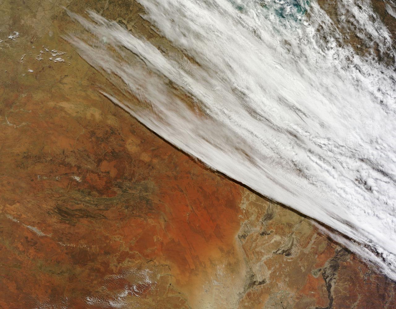 In late July 2013, a low pressure system off Australia’s southeast coast and moist onshore winds combined to create unsettled weather across central Australia – and a striking image of a broad cloud band across the stark winter landscape.  The Moderate Resolution Imaging Spectroradiometer (MODIS) aboard NASA’s Terra satellite captured this true-color image on July 22 at 01:05 UTC (10:35 a.m. Australian Central Standard Time). To the west of the low pressure trough the skies are clear and dry. To the east, the broad band of bright white clouds obscures the landscape. The system brought wind, precipitation and cooler temperatures to the region.  The same day as MODIS captured this image, the Naval Research Lab (NRL) published an edition of the Global Storm Tracker (GST), which gave a world-wide view of the low-pressure systems across the world. This tracker shows the entire cloud band across Australia, as well as the location of the low pressure system.  A good view of the Storm Tracker is provided by Red Orbit at: <a href="http://www.redorbit.com/media/uploads/2013/07/072213-weather-003-storm-tracker.jpg" rel="nofollow">www.redorbit.com/media/uploads/2013/07/072213-weather-003...</a>  Credit: NASA/GSFC/Jeff Schmaltz/MODIS Land Rapid Response Team  <b><a href="http://www.nasa.gov/audience/formedia/features/MP_Photo_Guidelines.html" rel="nofollow">NASA image use policy.</a></b>  <b><a href="http://www.nasa.gov/centers/goddard/home/index.html" rel="nofollow">NASA Goddard Space Flight Center</a></b> enables NASA’s mission through four scientific endeavors: Earth Science, Heliophysics, Solar System Exploration, and Astrophysics. Goddard plays a leading role in NASA’s accomplishments by contributing compelling scientific knowledge to advance the Agency’s mission.  <b>Follow us on <a href="http://twitter.com/NASA_GoddardPix" rel="nofollow">Twitter</a></b>  <b>Like us on <a href="http://www.facebook.com/pages/Greenbelt-MD/NASA-Goddard/395013845897?ref=tsd" rel="nofollow">Facebook</a></b>  <b>Find us on <a href="http://instagram.com/nasagoddard?vm=grid" rel="nofollow">Instagram</a></b>