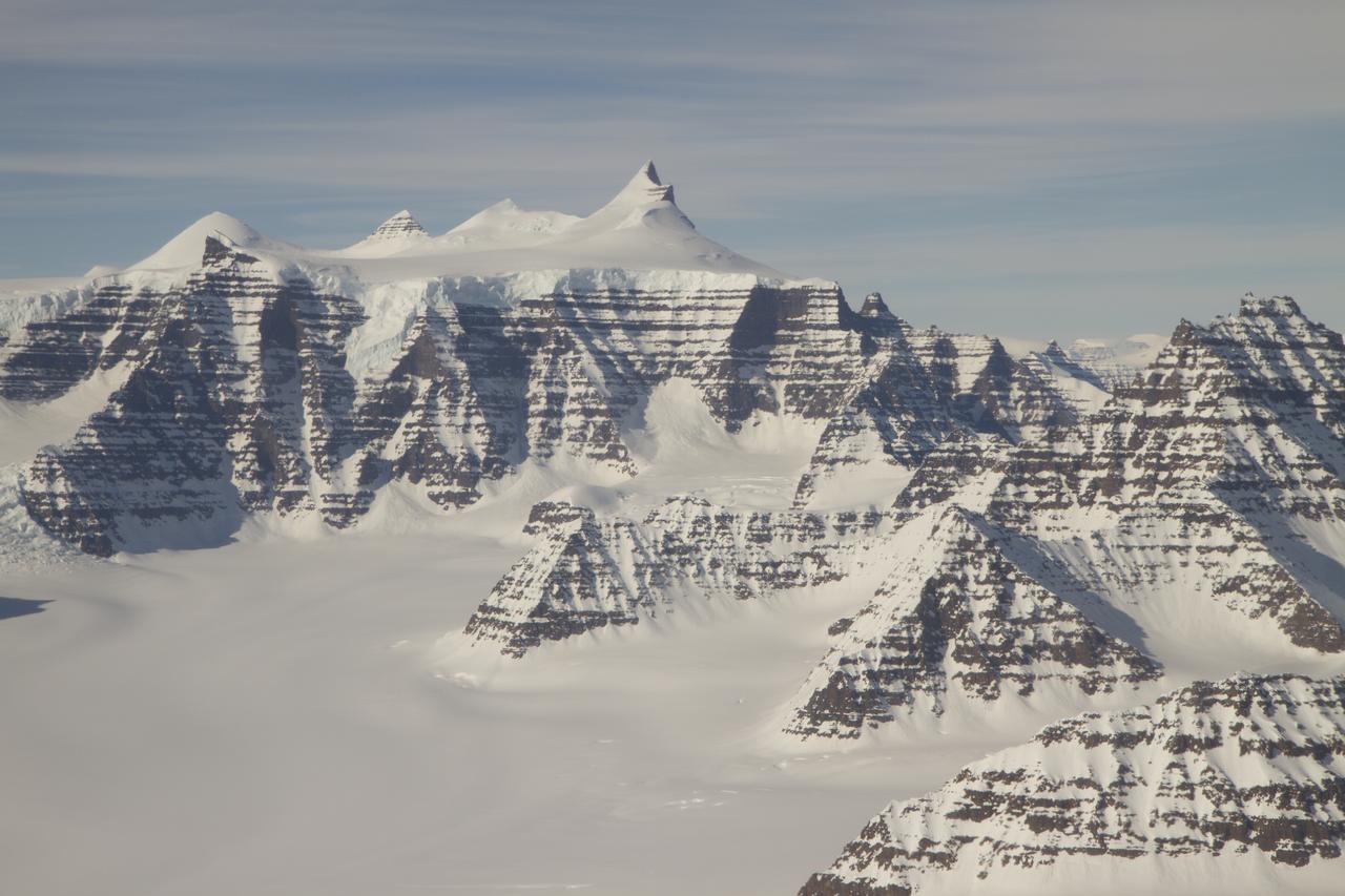 Mountain ridges showing the distinctive geology of the Geikie Plateau region in eastern Greenland, as seen from NASA's P-3B aircraft on April 16, 2012.  Credit: NASA/GSFC/Jefferson Beck  ===========  IceBridge, a six-year NASA mission, is the largest airborne survey of Earth's polar ice ever flown. It will yield an unprecedented three-dimensional view of Arctic and Antarctic ice sheets, ice shelves and sea ice. These flights will provide a yearly, multi-instrument look at the behavior of the rapidly changing features of the Greenland and Antarctic ice.  Data collected during IceBridge will help scientists bridge the gap in polar observations between NASA's Ice, Cloud and Land Elevation Satellite (ICESat) -- in orbit since 2003 -- and ICESat-2, planned for early 2016. ICESat stopped collecting science data in 2009, making IceBridge critical for ensuring a continuous series of observations.  IceBridge will use airborne instruments to map Arctic and Antarctic areas once a year. IceBridge flights are conducted in March-May over Greenland and in October-November over Antarctica. Other smaller airborne surveys around the world are also part of the IceBridge campaign.  To read more about IceBridge - Arctic 2012 go to: <a href="http://www.nasa.gov/mission_pages/icebridge/index.html" rel="nofollow">www.nasa.gov/mission_pages/icebridge/index.html</a>   <b><a href="http://www.nasa.gov/audience/formedia/features/MP_Photo_Guidelines.html" rel="nofollow">NASA image use policy.</a></b>  <b><a href="http://www.nasa.gov/centers/goddard/home/index.html" rel="nofollow">NASA Goddard Space Flight Center</a></b> enables NASA’s mission through four scientific endeavors: Earth Science, Heliophysics, Solar System Exploration, and Astrophysics. Goddard plays a leading role in NASA’s accomplishments by contributing compelling scientific knowledge to advance the Agency’s mission.  <b>Follow us on <a href="http://twitter.com/NASA_GoddardPix" rel="nofollow">Twitter</a></b>  <b>Like us on <a href="http://www.facebook.com/pages/Greenbelt-MD/NASA-Goddard/395013845897?ref=tsd" rel="nofollow">Facebook</a></b>  <b>Find us on <a href="http://instagrid.me/nasagoddard/?vm=grid" rel="nofollow">Instagram</a></b>