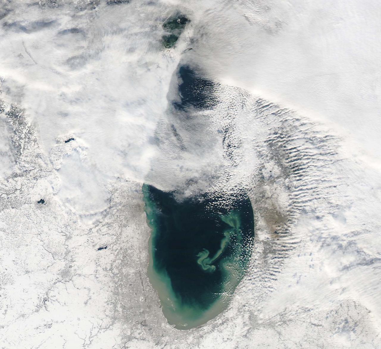 NASA image acquired December 17, 2010  In mid-December 2010, suspended sediments transformed the southern end of Lake Michigan. Ranging in color from brown to green, the sediment filled the surface waters along the southern coastline and formed a long, curving tendril extending toward the middle of the lake. The Moderate Resolution Imaging Spectroradiometer (MODIS) on NASA’s Aqua satellite captured these natural-color images on December 17, 2010 (top), and December 10, 2010 (bottom).  Such sediment clouds are not uncommon in Lake Michigan, where winds influence lake circulation patterns. A scientificpaper published in 2007 described a model of the circulation, noting that while the suspended particles mostly arise from lake-bottom sediments along the western shoreline, they tend to accumulate on the eastern side. When northerly winds blow, two circulation gyres, rotating in opposite directions, transport sediment along the southern shoreline. As the northerly winds die down, the counterclockwise gyre predominates, and the smaller, clockwise gyre dissipates. Clear water—an apparent remnant of the small clockwise gyre—continues to interrupt the sediment plume.  George Leshkevich, a researcher with the U.S. National Oceanic and Atmospheric Administration, explains that the wind-driven gyres erode lacustrine clay (very fine lakebed sediment) on the western shore before transporting it, along with re-suspended lake sediments, to the eastern shore. On the eastern side, the gyre encounters a shoreline bulge that pushes it toward the lake’s central southern basin, where it deposits the sediments.  The sediment plume on December 17 followed a windy weather front in the region on December 16.  NASA image courtesy MODIS Rapid Response Team at NASA GSFC. Caption by Michon Scott.  Instrument: Aqua - MODIS  <b><a href="http://www.nasa.gov/centers/goddard/home/index.html" rel="nofollow">NASA Goddard Space Flight Center</a></b> enables NASA’s mission through four scientific endeavors: Earth Science, Heliophysics, Solar System Exploration, and Astrophysics. Goddard plays a leading role in NASA’s accomplishments by contributing compelling scientific knowledge to advance the Agency’s mission.  <b>Follow us on <a href="http://twitter.com/NASA_GoddardPix" rel="nofollow">Twitter</a></b>  <b>Join us on <a href="http://www.facebook.com/pages/Greenbelt-MD/NASA-Goddard/395013845897?ref=tsd" rel="nofollow">Facebook</a></b>  To read more about this image go to: <a href="http://earthobservatory.nasa.gov/IOTD/view.php?id=48511" rel="nofollow">earthobservatory.nasa.gov/IOTD/view.php?id=48511</a>