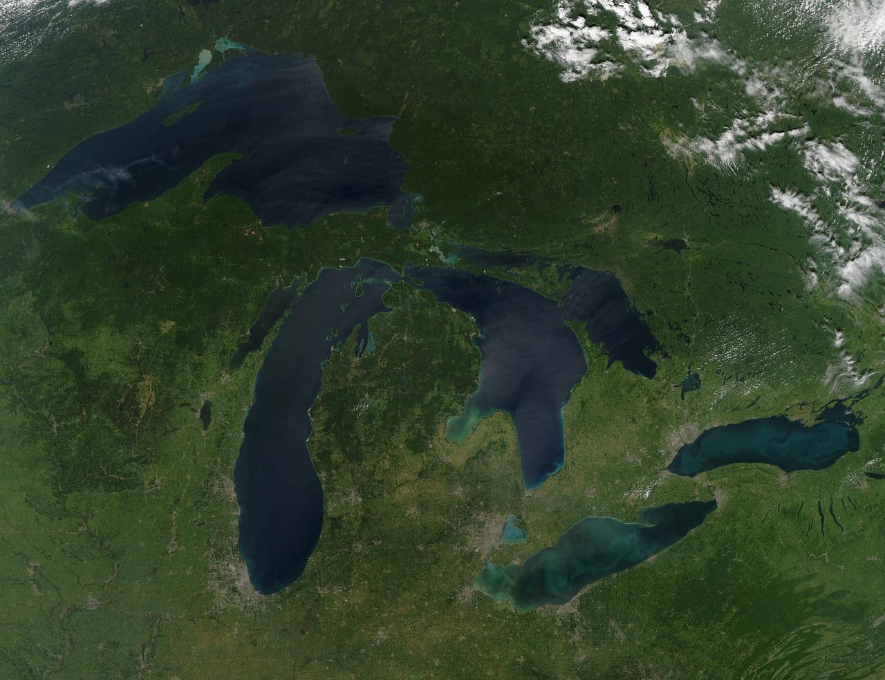 NASA image acquired August 28, 2010  Late August 2010 provided a rare satellite view of a cloudless summer day over the entire Great Lakes region. North Americans trying to sneak in a Labor Day weekend getaway on the lakes were hoping for more of the same.  The Great Lakes comprise the largest collective body of fresh water on the planet, containing roughly 18 percent of Earth's supply. Only the polar ice caps contain more fresh water. The region around the Great Lakes basin is home to more than 10 percent of the population of the United States and 25 percent of the population of Canada.  Many of those people have tried to escape record heat this summer by visiting the lakes. What they found, according to The Hamilton Spectator, was record-breaking water temperatures fueled by record-breaking air temperatures in the spring and summer. By mid-August, the waters of Lake Superior were 6 to 8°C (11 to 14°F) above normal. Lake Michigan set records at about 4°C (7°F) above normal. The other three Great Lakes – Huron, Erie, and Ontario -- were above normal temperatures, though no records were set.  The image was gathered by the Moderate Resolution Imaging Spectroradiometer (MODIS) on NASA’s Aqua satellite at 1:30 p.m. Central Daylight Time (18:30 UTC) on August 28. Open water appears blue or nearly black. The pale blue and green swirls near the coasts are likely caused by algae or phytoplankton blooms, or by calcium carbonate (chalk) from the lake floor. The sweltering summer temperatures have produced an unprecedented bloom of toxic blue-green algae in western Lake Erie, according to the Cleveland Plain Dealer.  NASA image by Jeff Schmaltz, MODIS Rapid Response Team, Goddard Space Flight Center. Caption by Mike Carlowicz.  Instrument: Aqua - MODIS  Click here to see more images from <b><a href="#//earthobservatory.nasa.gov/" rel="nofollow"> NASA Goddard’s Earth Observatory</a></b>  <b><a href="http://www.nasa.gov/centers/goddard/home/index.html" rel="nofollow">NASA Goddard Space Flight Center</a></b>  is home to the nation's largest organization of combined scientists, engineers and technologists that build spacecraft, instruments and new technology to study the Earth, the sun, our solar system, and the universe.  <b>Follow us on <a href="http://twitter.com/NASA_GoddardPix" rel="nofollow">Twitter</a></b>  <b>Join us on <a href="http://www.facebook.com/pages/Greenbelt-MD/NASA-Goddard/395013845897?ref=tsd" rel="nofollow">Facebook</a></b>