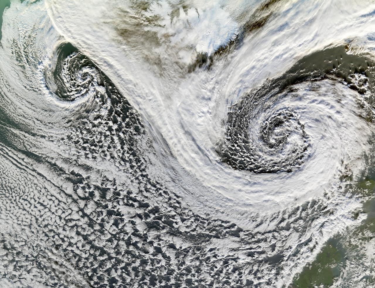 A cyclone is a low-pressure area of winds that spiral inwards. Although tropical storms most often come to mind, these spiraling storms can also form at mid- and high latitudes. Two such cyclones formed in tandem in November 2006. The Moderate Resolution Imaging Spectroradiometer (MODIS) flying onboard NASA’s Terra satellite took this picture on November 20. This image shows the cyclones south of Iceland. Scotland appears in the lower right. The larger and perhaps stronger cyclone appears in the east, close to Scotland.  Cyclones at high and mid-latitudes are actually fairly common, and they drive much of the Earth’s weather. In the Northern Hemisphere, cyclones move in a counter-clockwise direction, and both of the spiraling storms in this image curl upwards toward the northeast then the west. The eastern storm is fed by thick clouds from the north that swoop down toward the storm in a giant “V” shape on either side of Iceland. Skies over Iceland are relatively clear, allowing some of the island to show through. South of the storms, more diffuse cloud cover swirls toward the southeast.  Credit: NASA  <b><a href="http://www.nasa.gov/centers/goddard/home/index.html" rel="nofollow">NASA Goddard Space Flight Center</a></b>  is home to the nation's largest organization of combined scientists, engineers and technologists that build spacecraft, instruments and new technology to study the Earth, the sun, our solar system, and the universe.   <b>Follow us on <a href="http://twitter.com/NASA_GoddardPix" rel="nofollow">Twitter</a></b>  <b>Join us on <a href="http://www.facebook.com/pages/Greenbelt-MD/NASA-Goddard/395013845897?ref=tsd" rel="nofollow">Facebook</a></b>