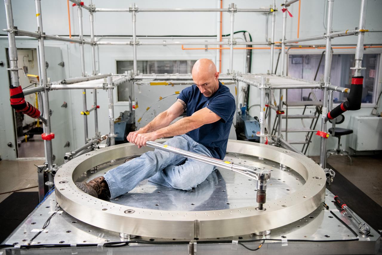 Engineering Technician Ryan Fischer torques the Force Gauge Ring on to the vibe table in preparation for vibration testing of the PACE spacecraft bus at NASA Goddard Space Flight Center in Greenbelt Maryland on June 16th, 2021.   Photographer: Denny Henry – Goddard Space Flight Center