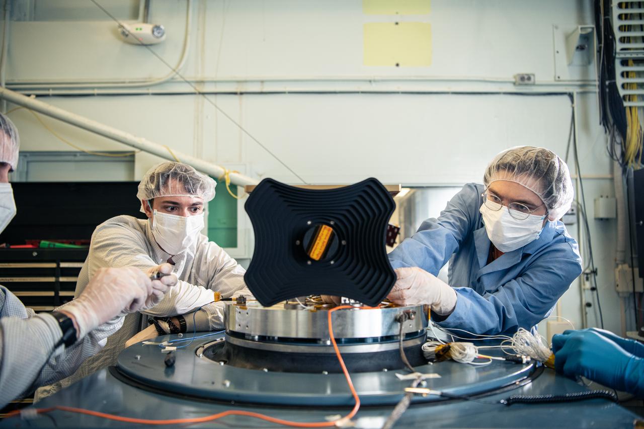 UMBC Earth and Space Institute engineers Ian Decker (left) and Danny Nelson (right) attach the Hyper-Angular Rainbow Polarimeter #2 (HARP2) instrument to the shaker table for vibration testing at NASA's Goddard Space Flight Center in Greenbelt Maryland on August 8th, 2022.  HARP2 is one of three instruments on NASA's Plankton, Aerosol, Cloud, ocean Ecosystem (PACE) observatory, it was designed and built by UMBC's Earth and Space Institute. 