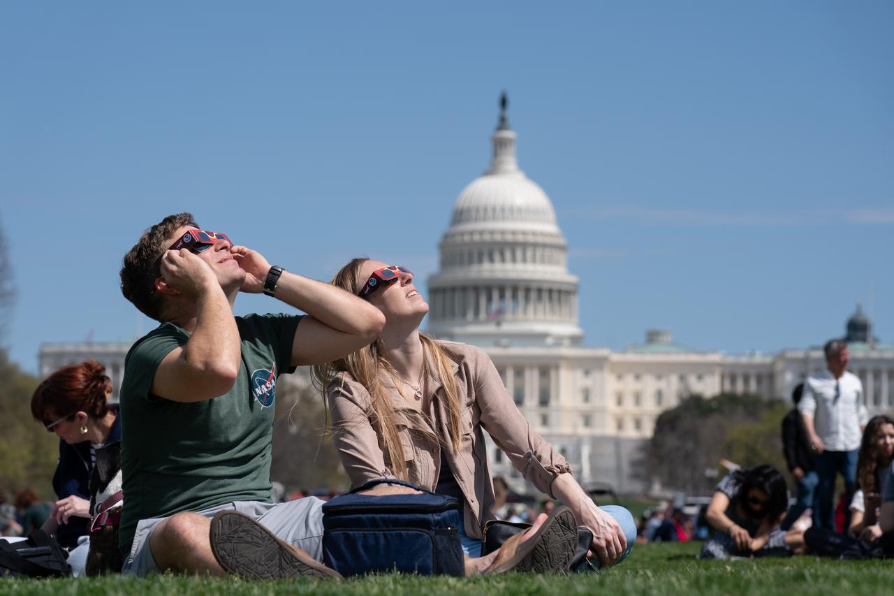 Neil Tublin and Reigna Pierce view the partial solar eclipse in Washington, DC, Monday, April 8, 2024. A total solar eclipse swept across a narrow portion of the North American continent from Mexico’s Pacific coast to the Atlantic coast of Newfoundland, Canada. A partial solar eclipse was visible across the entire North American continent along with parts of Central America and Europe. Photo Credit: (NASA/Denny Henry)