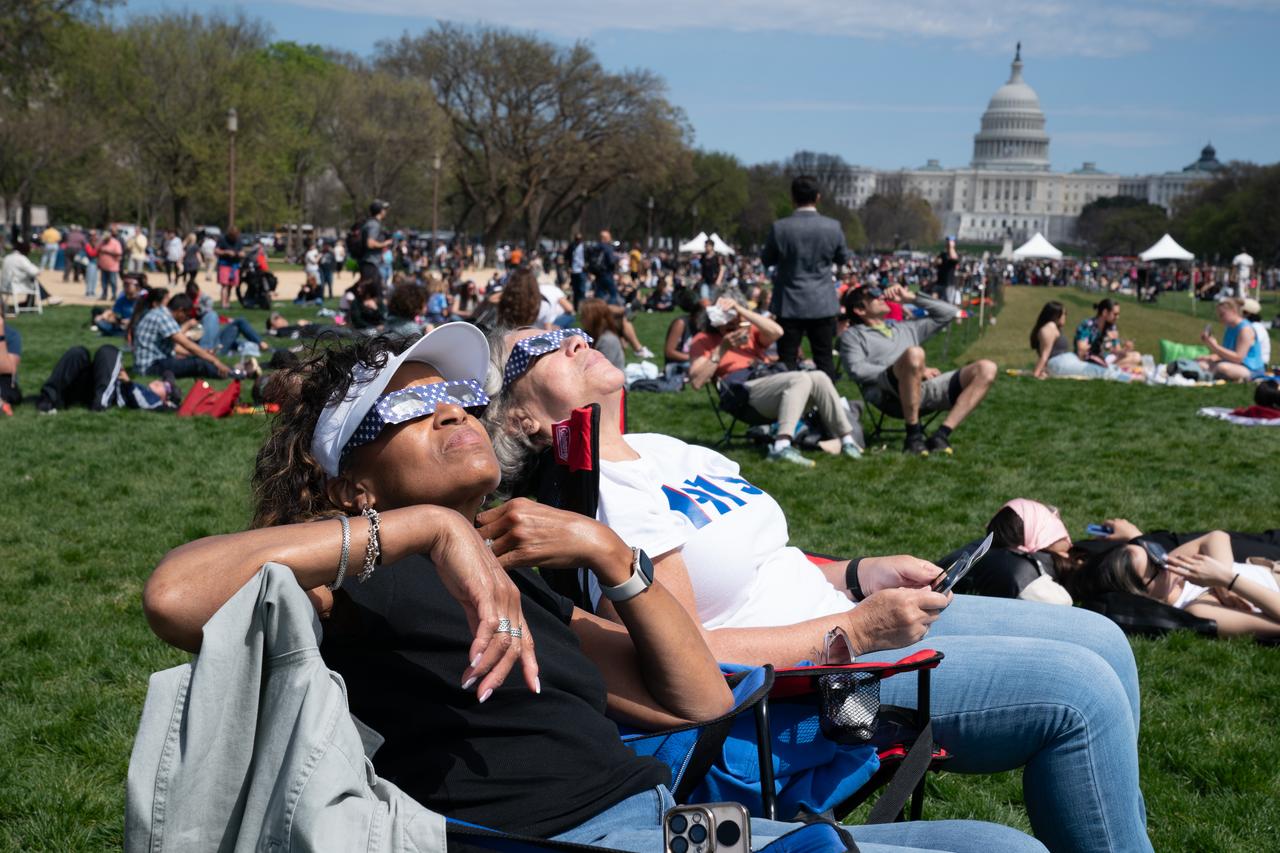 Patricia Jones (left) and Renee Chapman (right) view a partial solar eclipse in Washington, DC, Monday, April 8, 2024. A total solar eclipse swept across a narrow portion of the North American continent from Mexico’s Pacific coast to the Atlantic coast of Newfoundland, Canada. A partial solar eclipse was visible across the entire North American continent along with parts of Central America and Europe. Photo Credit: (NASA/Denny Henry)