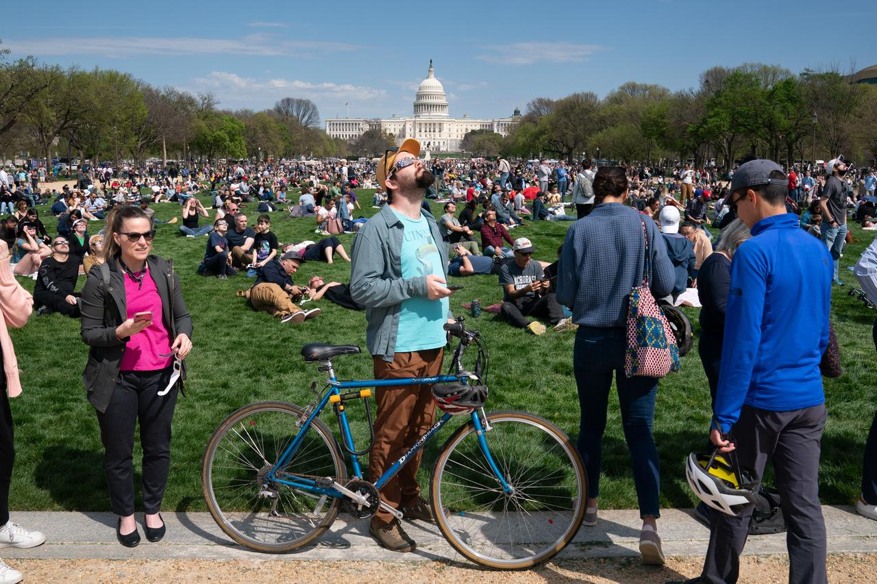 Mike Tyska (center) views a partial solar eclipse in Washington, DC, Monday, April 8, 2024. A total solar eclipse swept across a narrow portion of the North American continent from Mexico’s Pacific coast to the Atlantic coast of Newfoundland, Canada. A partial solar eclipse was visible across the entire North American continent along with parts of Central America and Europe. Photo Credit: (NASA/Denny Henry)