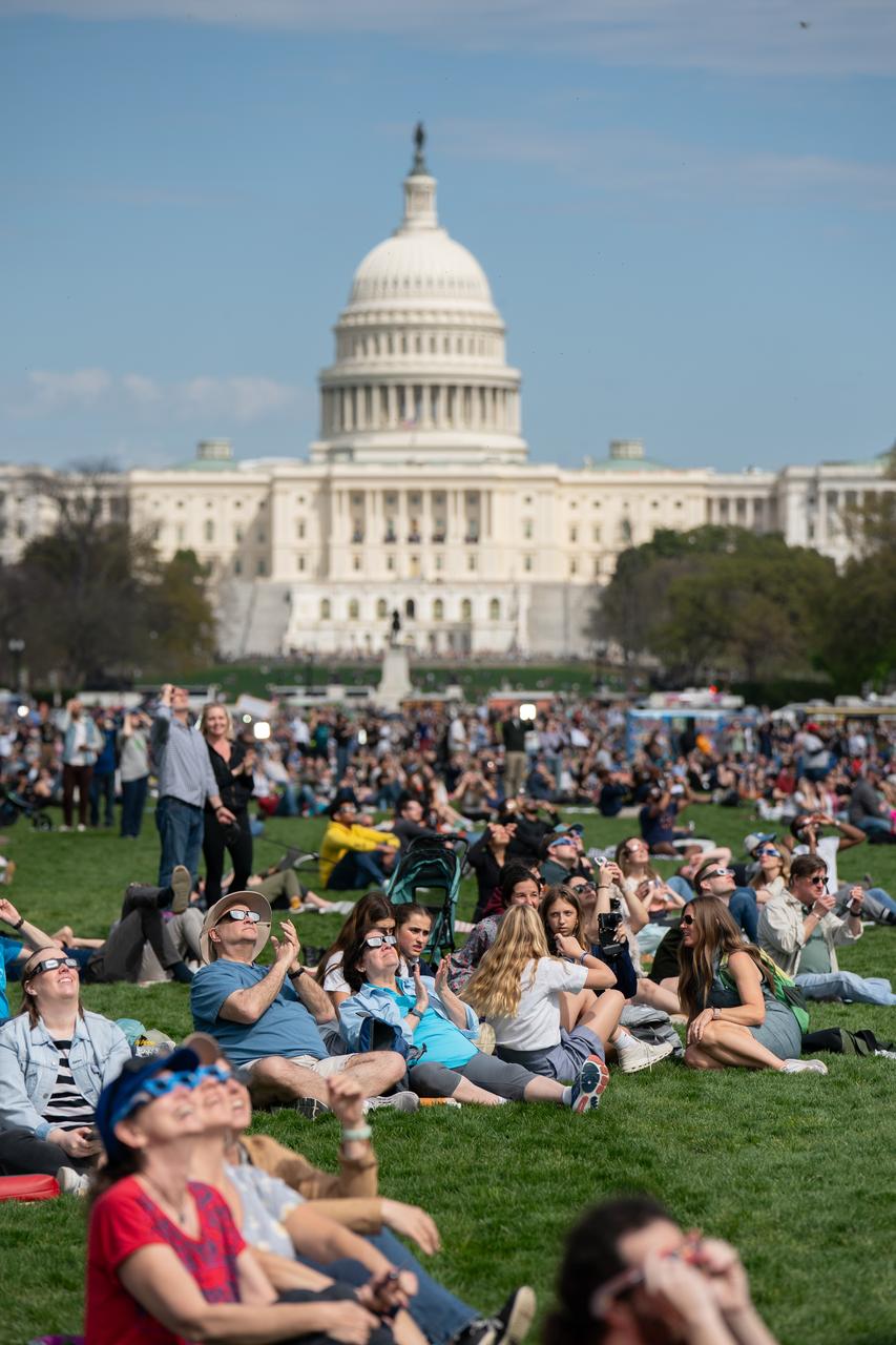 Spectators on the National Mall during a partial solar eclipse in Washington, DC, Monday, April 8, 2024. A total solar eclipse swept across a narrow portion of the North American continent from Mexico’s Pacific coast to the Atlantic coast of Newfoundland, Canada. A partial solar eclipse was visible across the entire North American continent along with parts of Central America and Europe. Photo Credit: (NASA/Denny Henry)