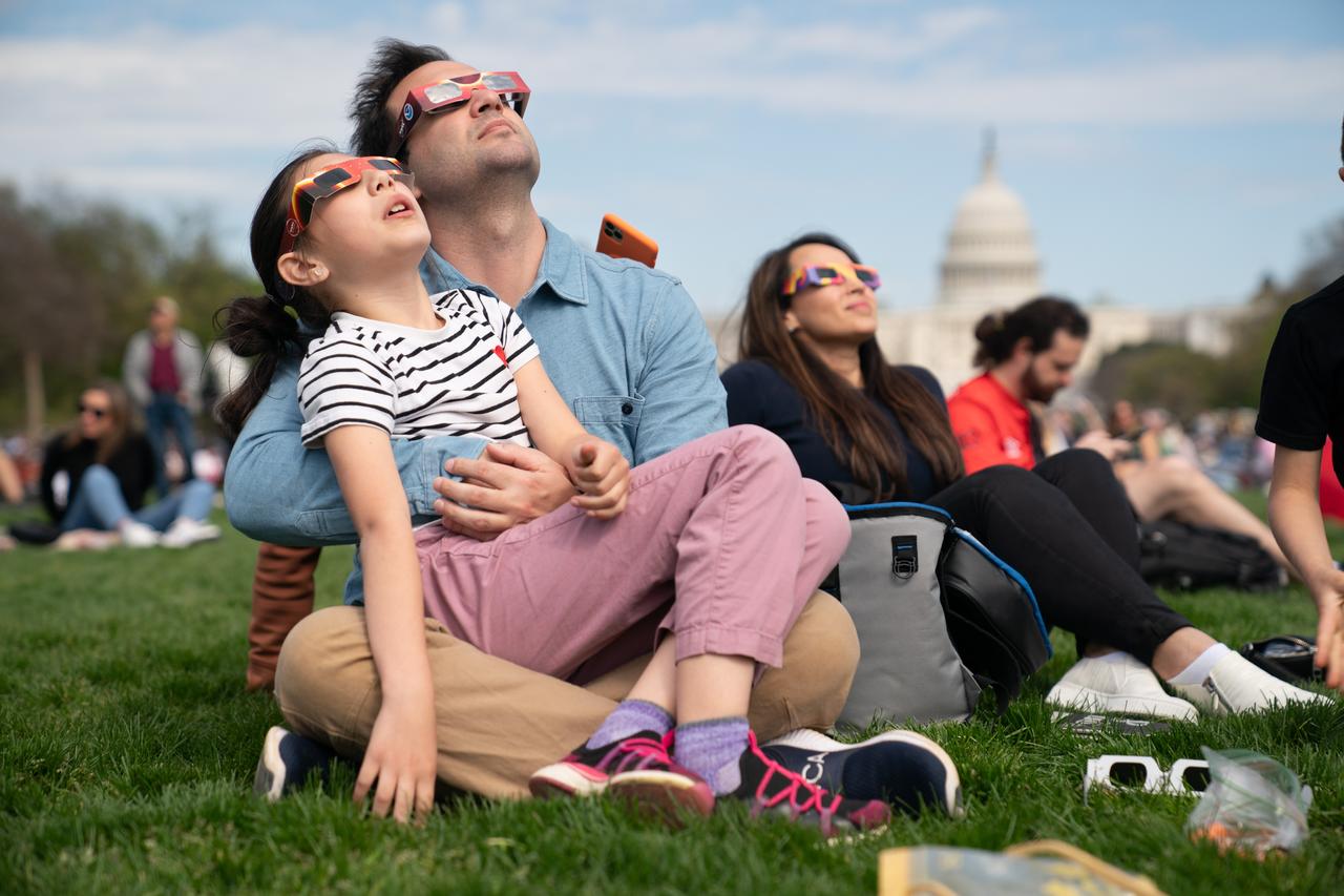 Miranda (9) and Cameron Dyal view a partial solar eclipse in Washington, DC, Monday, April 8, 2024. A total solar eclipse swept across a narrow portion of the North American continent from Mexico’s Pacific coast to the Atlantic coast of Newfoundland, Canada. A partial solar eclipse was visible across the entire North American continent along with parts of Central America and Europe. Photo Credit: (NASA/Denny Henry)