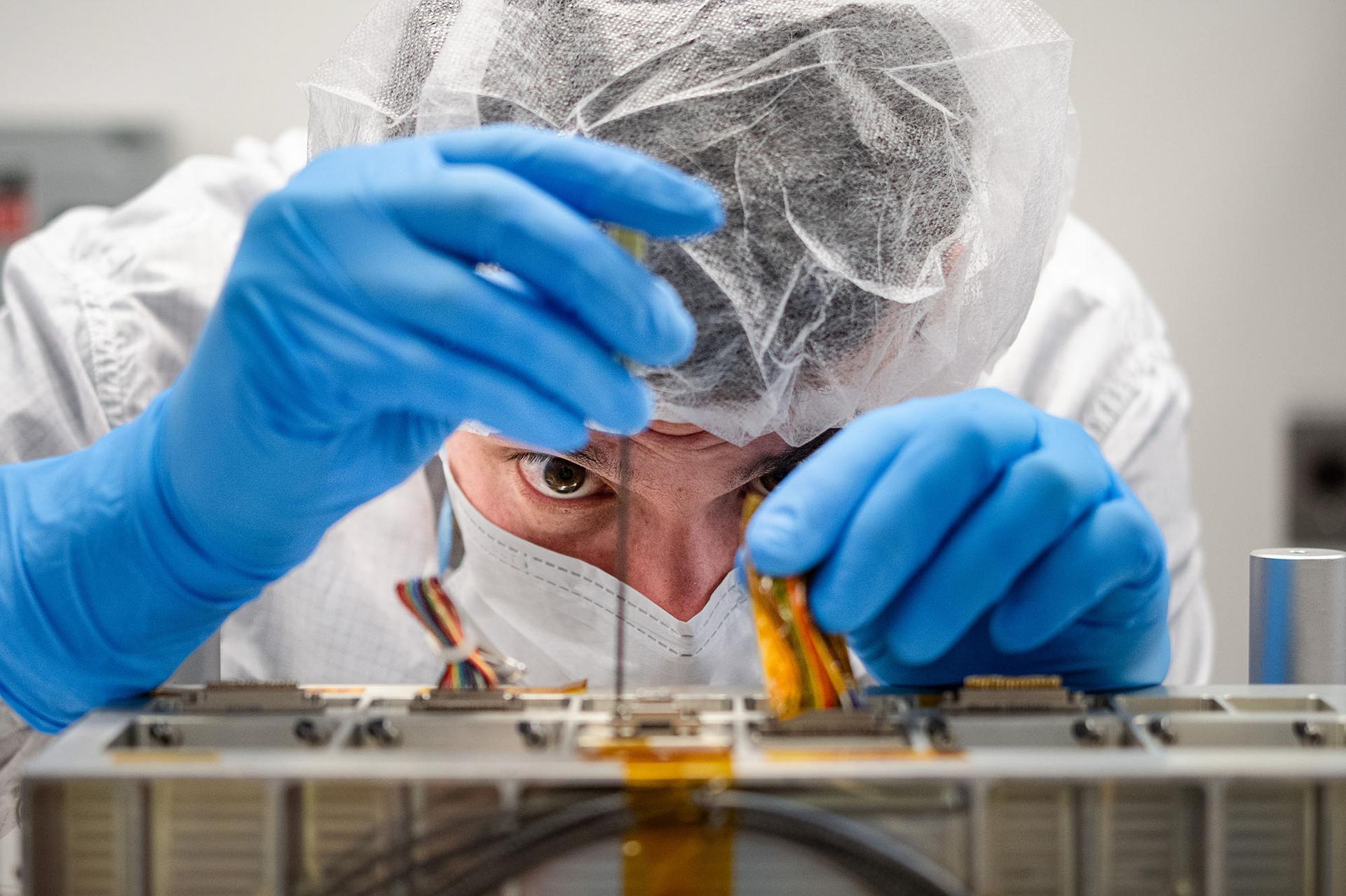 Technician Kyle Guzek installs a connector on the Laser Optical Module for the Laser Interferometer Space Antenna (LISA) mission at NASA's Goddard Space Flight Center in Greenbelt, Maryland on May 27th, 2025. Photo Credit: (NASA/Denny Henry)