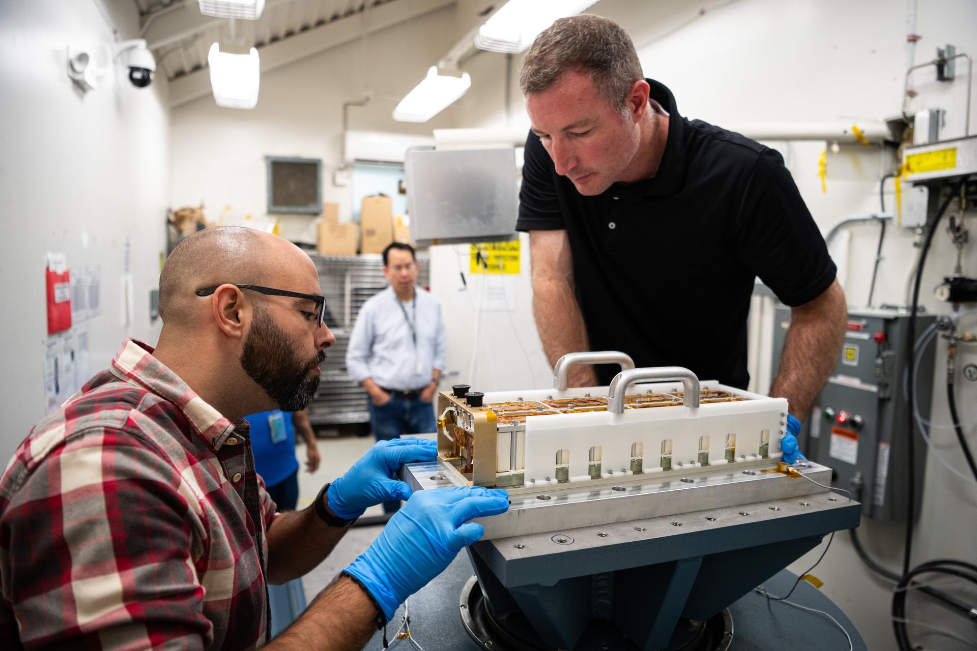 Mechanical Engineer  John Seixal (left) and Engineering Technician Alex Schaeffer prepare the Lunar Environment Monitoring Station (LEMS) flight battery for vibration testing in a lab at NASA's Goddard Space Flight Center in Greenbelt, Maryland on September 29th, 2025. LEMS is a compact, autonomous, and self-sustaining seismometer suite designed to carry out continuous, long-term, monitoring of the lunar seismic environment at the South Polar region.  NASA/Denny Henry.