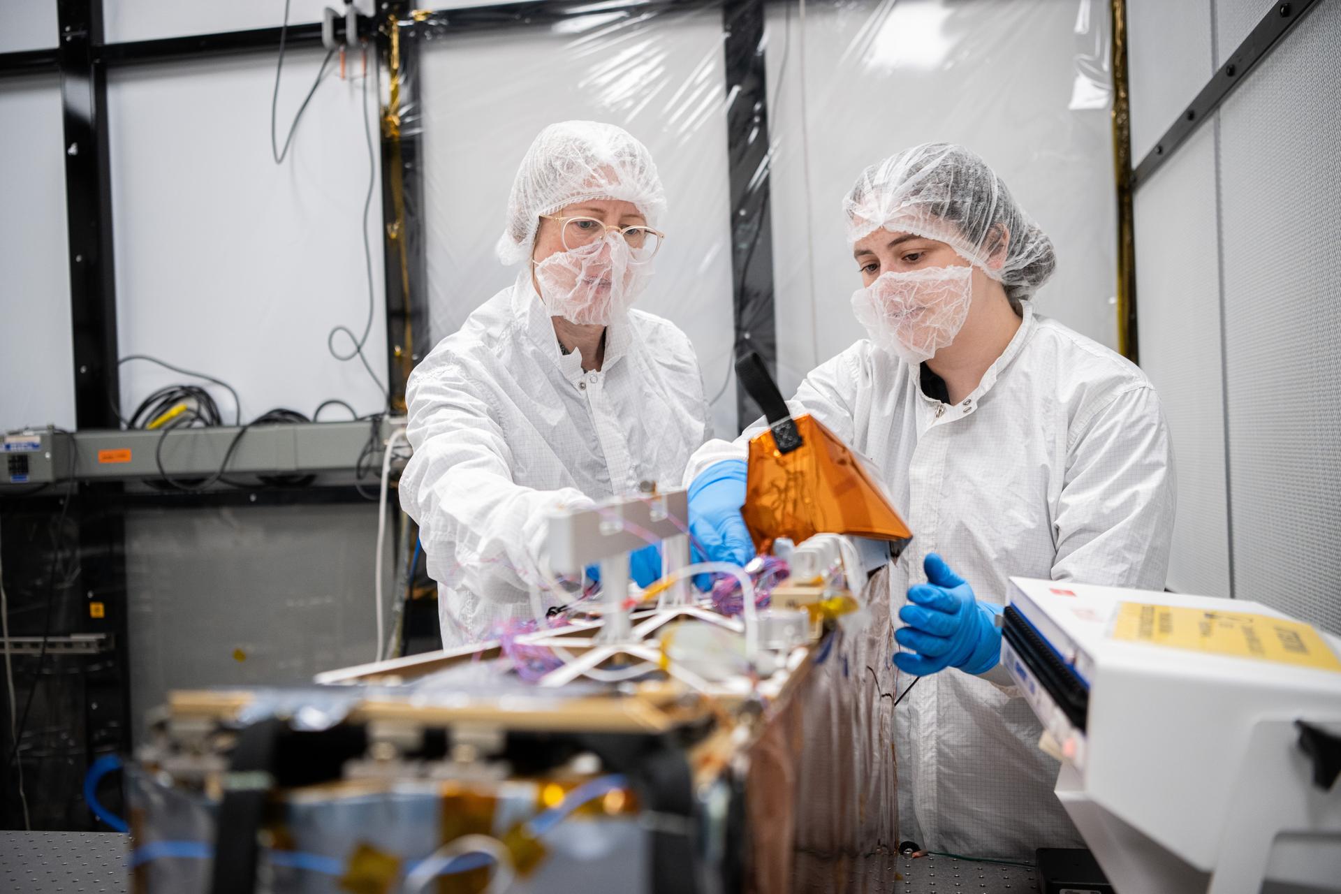 Naoma McCall (Left), Science Co-Investigator and deployment lead and Mechanical Engineer Brie Ludwig inspect the Lunar Environment Monitoring Station (LEMS) instrument in the cleanroom at Goddard Space Flight Center in Greenbelt Md. on February 5th, 2026. LEMS is a compact, autonomous, and self-sustaining seismometer suite designed to carry out continuous, long-term, monitoring of the lunar seismic environment at the South Polar region. Photo Credit: NASA/Denny Henry 