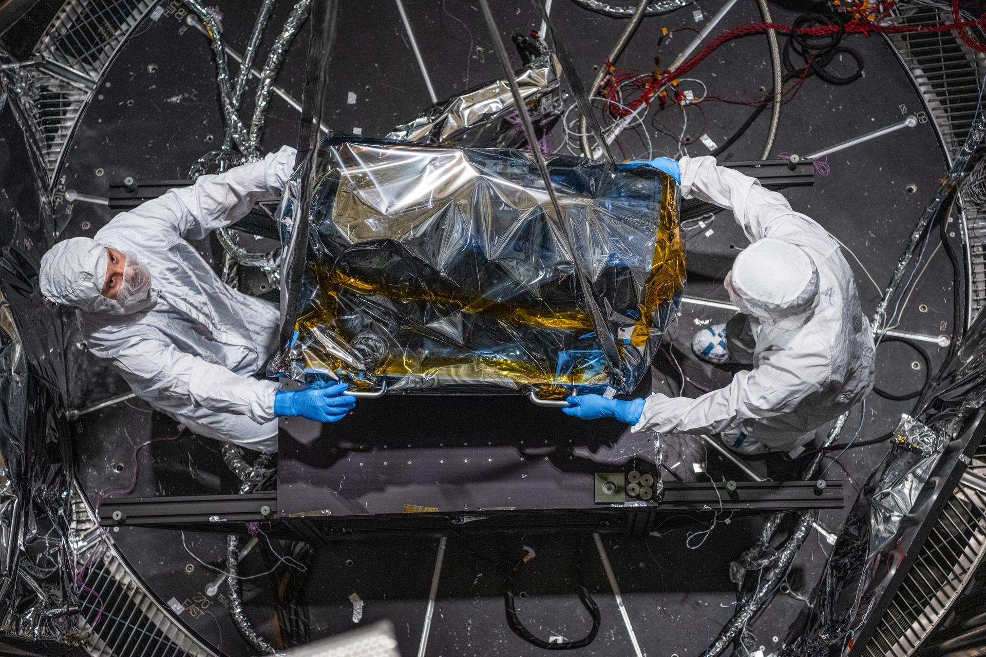 Engineering Technician Eric Norris, and Mechanical Engineer Mitchell Hamann guide the Lunar Environment Monitoring Station (LEMS) instrument in to the Thermal Vacuum Chamber preparation for testing  at Goddard Space Flight Center, Greenbelt Md., March 30, 2026. LEMS is a compact, autonomous, and self-sustaining seismometer suite designed to carry out continuous, long-term, monitoring of the lunar seismic environment at the South Polar region. Photo Credit: NASA/Denny Henry