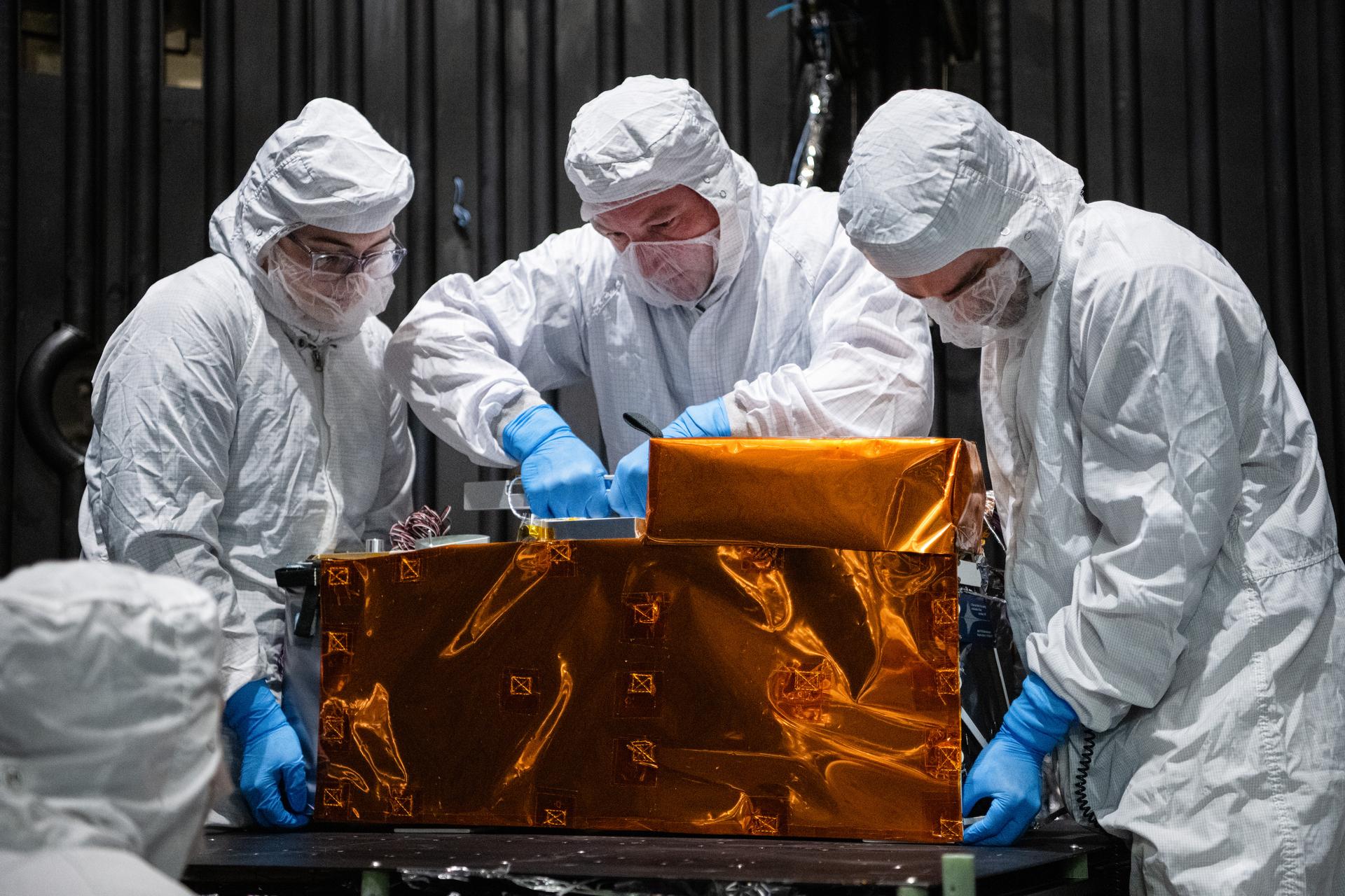 From left, mechanical engineer Gabrielle Ludwig, technician Alex Schaeffer, and mechanical engineer Mitchell Hamann install the Lunar Environment Monitoring Station (LEMS) instrument onto a test plate in a thermal vacuum chamber at Goddard Space Flight Center, Greenbelt Md., March 30, 2026. LEMS is a compact, autonomous, and self-sustaining seismometer suite designed to carry out continuous, long-term, monitoring of the lunar seismic environment at the South Polar region. Photo Credit: NASA/Denny Henry