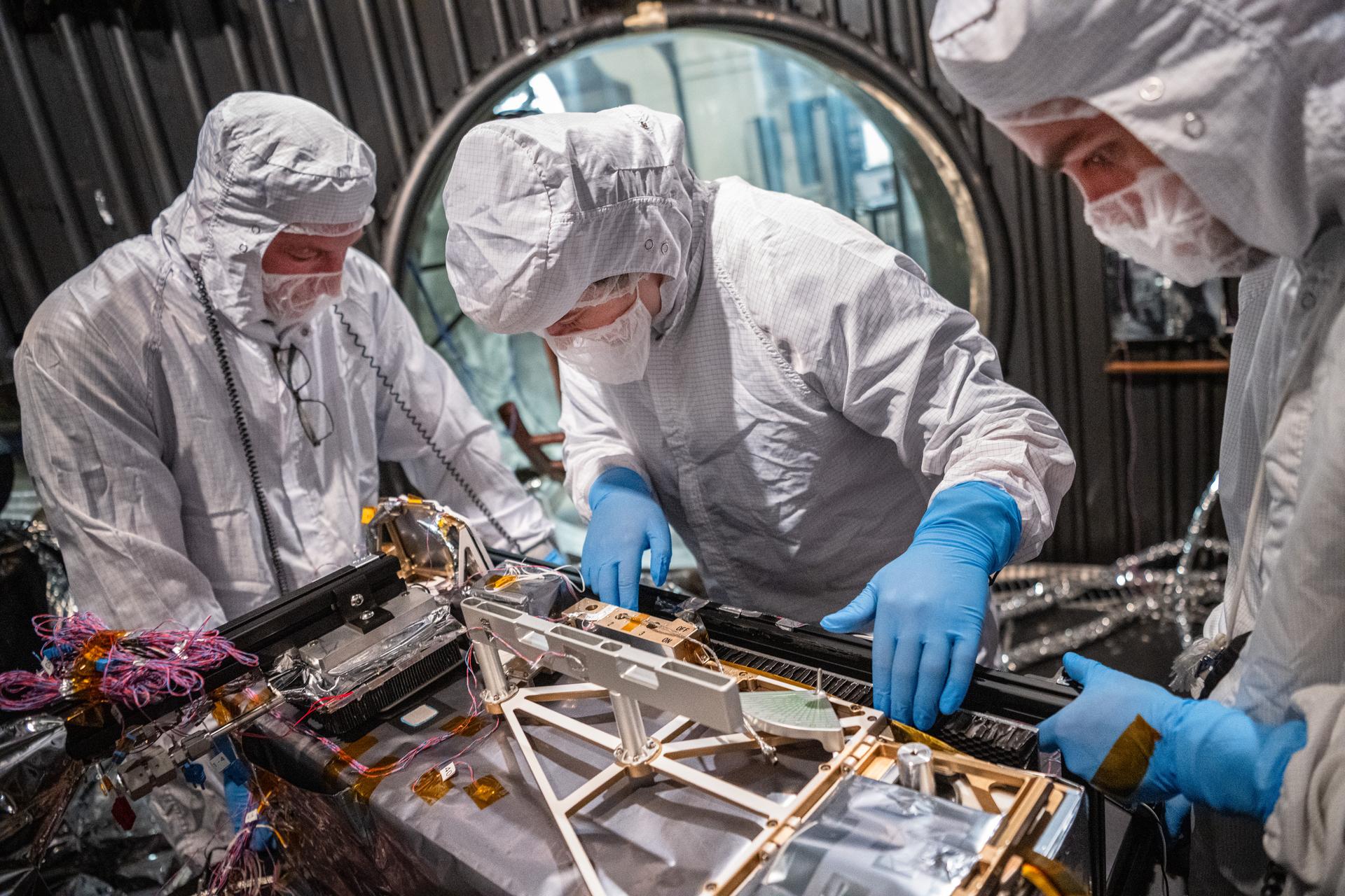 (L-R) Engineering Technician Alex Schaeffer, Mechanical Engineer Brie Ludwig , and Mechanical Engineer Mitchell Hamann inspect the Lunar Environment Monitoring Station (LEMS) instrument in preparation for testing in a thermal vacuum chamber at Goddard Space Flight Center in Greenbelt Md. on March 31, 2026. LEMS is a compact, autonomous, and self-sustaining seismometer suite designed to carry out continuous, long-term, monitoring of the lunar seismic environment at the South Polar region. Photo Credit: NASA/Denny Henry