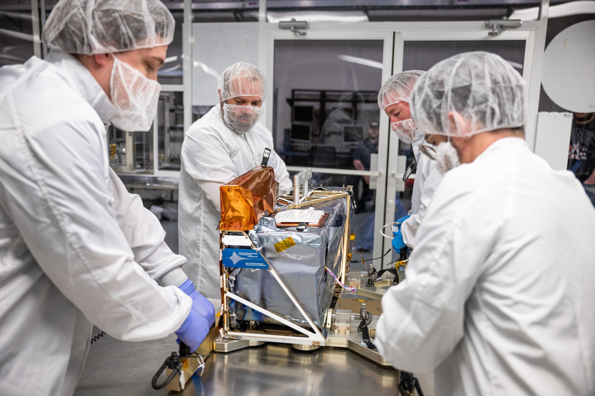 From left, systems safety engineer Kenny Porter, Morehead State University integration and testing engineer Ryan Collins, technician Alex Schaeffer, and mechanical engineer Mitchell Hamann lift the Lunar Environment Monitoring Station (LEMS) instrument during testing at the Space Science Center at Morehead State University in Morehead, KY on June 5, 2026. Morehead State University provided LEMS’ telecommunication system and will operate the instrument on the surface. LEMS is a compact, autonomous, and self-sustaining seismometer suite designed to carry out continuous, long-term, monitoring of the lunar seismic environment at the South Polar region. Photo Credit: NASA/Denny Henry