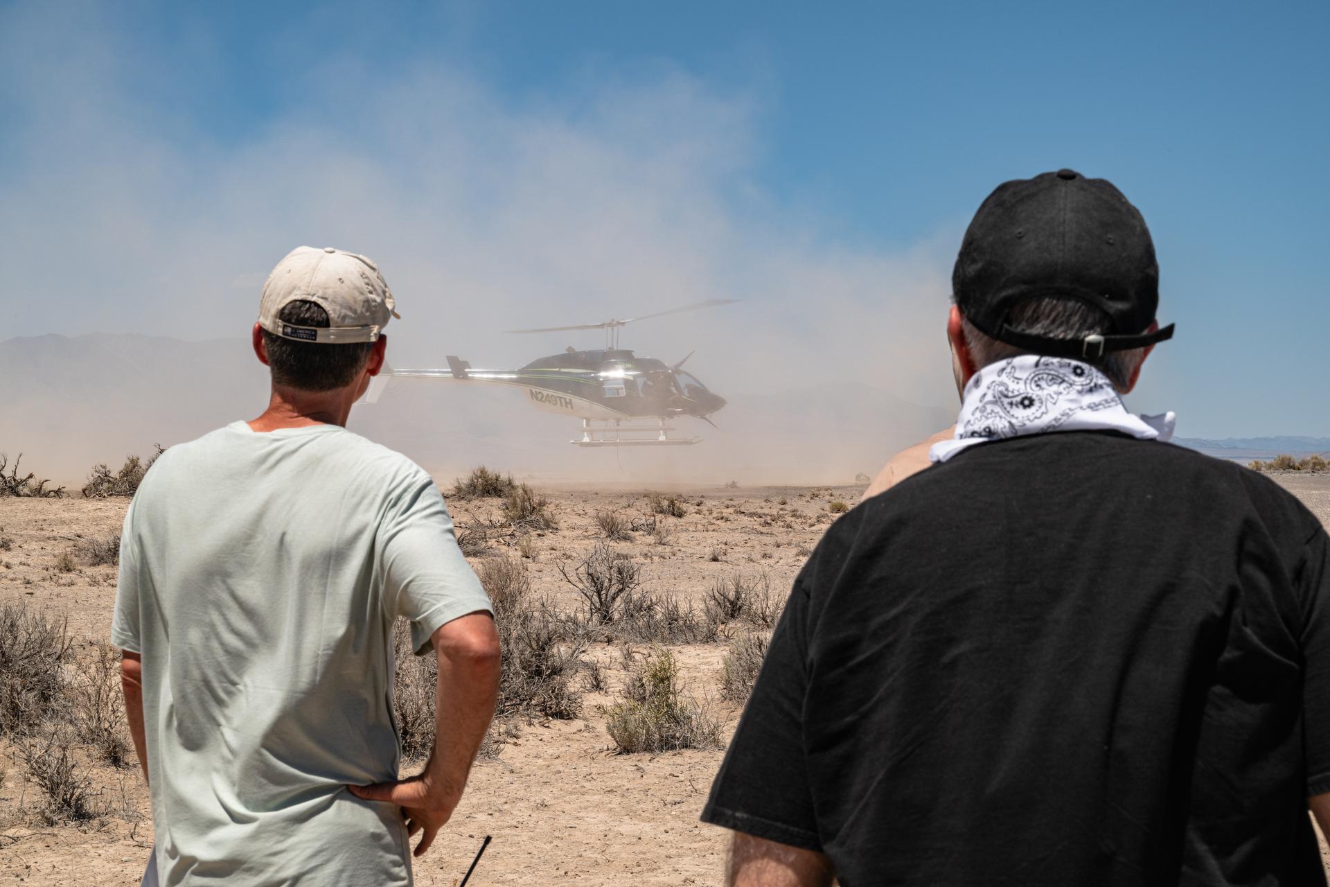 Brent Bos, left, and Jim Garvin, right, watch the helicopter carrying the VADIX payload lift off from Crater Island, Utah, June 23, 2026. VADIX is a test of the camera system that will one day fly aboard NASA’s DAVINCI mission probe to Venus. NASA/Mike Guinto