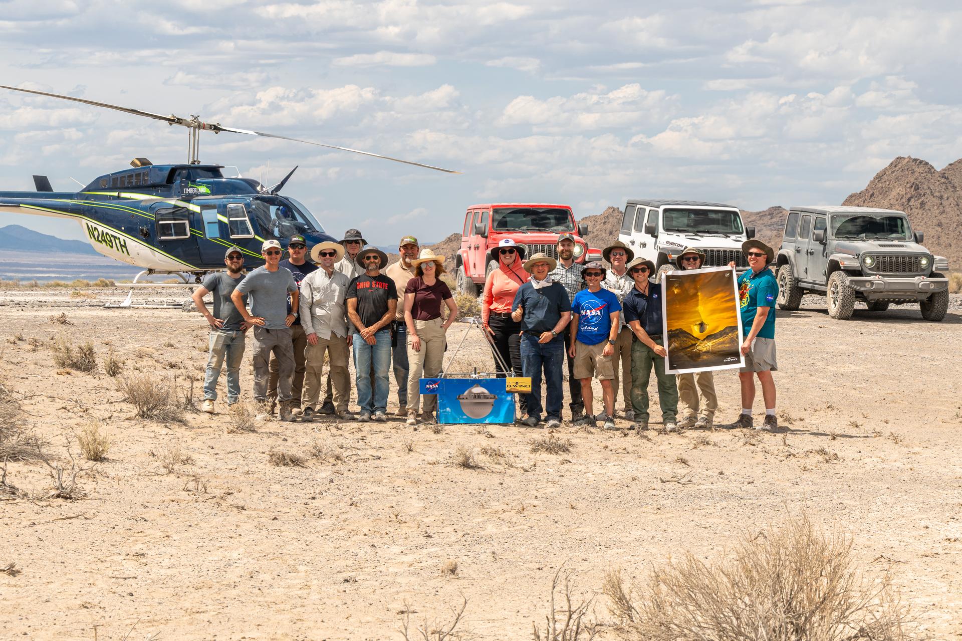 The DAVINCI VADIX team, from left to right, Mike Guinto, Brent Bos, Jason Burt, Dan Gallagher,Joe Turner, Ben Schumacher, Mike Vitulio, Erika Kohler, Lacey Young, Jim Garvin, Christian Tate, Phil Coulter, Mike Ravine, Matt Mullin, Bob Podgurski, Nick Lang; pose for a group photo in front of their vehicles at Crater Island, Utah, June 25, 2026. This area was the site of a series of tests (June 23-25, 2026) of the camera system that will one day fly aboard NASA’s DAVINCI mission to Venus. NASA/Mike Guinto