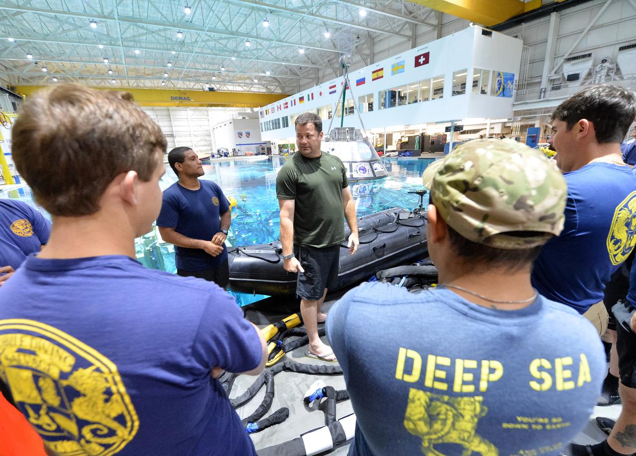 Tim Goddard, center, NASA Open Water Recovery Operations director, briefs U.S. Navy divers, Air Force pararescuemen and Coast Guard rescue swimmers during training in the Neutral Buoyancy Laboratory at NASA’s Johnson Space Center in Houston. The group will practice Orion underway recovery techniques using a test version of the Orion spacecraft. Training will help the team prepare for Underway Recovery Test 5 for Exploration Mission 1 aboard the USS San Diego in the Pacific Ocean off the coast of California in October. The Ground Systems Development and Operations Program, along with the U.S. Navy and Lockheed Martin, are preparing the recovery team, hardware and operations to support EM-1 recovery. 