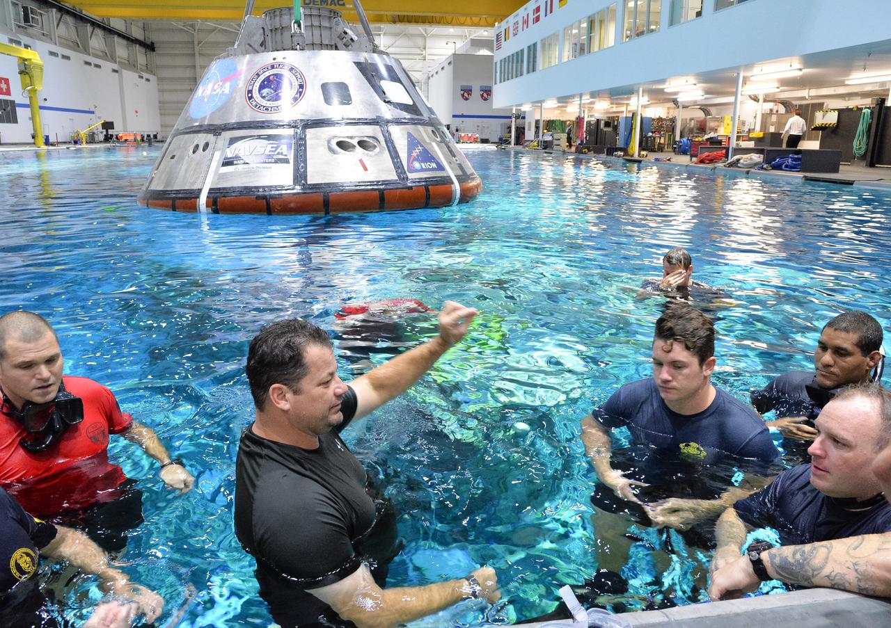 Tim Goddard, center, NASA Open Water Recovery Operations director, reviews recovery procedures with U.S. Navy divers, Air Force pararescuemen and Coast Guard rescue swimmers during training in the Neutral Buoyancy Laboratory at NASA’s Johnson Space Center in Houston. The group is practicing Orion underway recovery techniques using a test version of the Orion spacecraft. Training will help the team prepare for Underway Recovery Test 5 for Exploration Mission 1 aboard the USS San Diego in the Pacific Ocean off the coast of California in October. The Ground Systems Development and Operations Program, along with the U.S. Navy and Lockheed Martin, are preparing the recovery team, hardware and operations to support EM-1 recovery. 