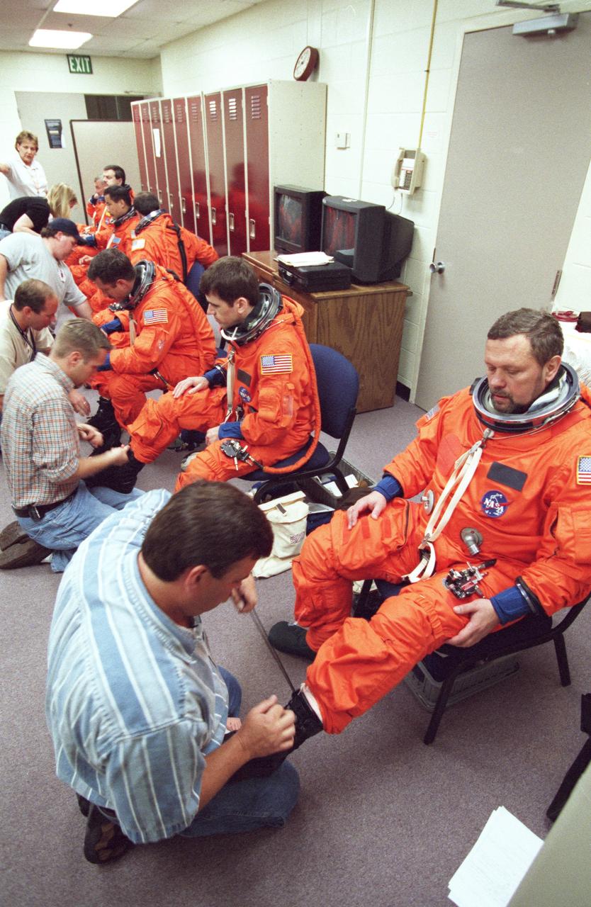 JSC2000-02217 (March 2000) --- United Space Alliance suit technician Mike  Birkenseher helps cosmonaut Boris V. Morukov with the donning of his launch and entry suit (LES) prior to STS-106 training in the Systems Integration Facility at the Johnson Space Center  (JSC).