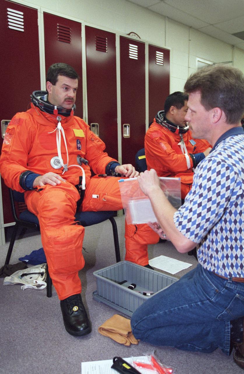 JSC2000-02218 (March 2000) --- United Space Alliance (USA) suit technician  Brad Milling assists astronaut Scott D. Altman, pilot for STS-106, with his launch and entry suit.  Altman was getting ready for a training session in the Systems Integration Facility at the Johnson Space Center (JSC). Astronaut Edward T. Lu, mission specialist, can be seen in the background.
