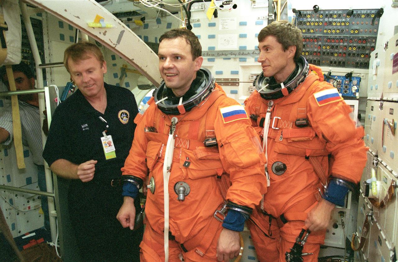 JSC2000-04070 (12 May 2000) --- Two cosmonauts assigned to ISS Expedition One participate in shuttle descent and egress training on the mid deck of the Crew Compartment Trainer (CCT) at the Johnson Space Center's systems integration facility. Pictured in the burnt-orange pressure suits are Yuri Gidzenko (center), Soyuz commander; and   Sergei Krikalev, flight engineer.  At left is astronaut Andrew S.W. Thomas who assisted the crew members in this training session.  Gidzenko, Krikalev and astronaut William Shepherd (not in picture), mission commander, were training for descent procedures, both routine and contigency measures, in the  session.  Their stay aboard ISS will  conclude when they return to Earth aboard a shuttle.