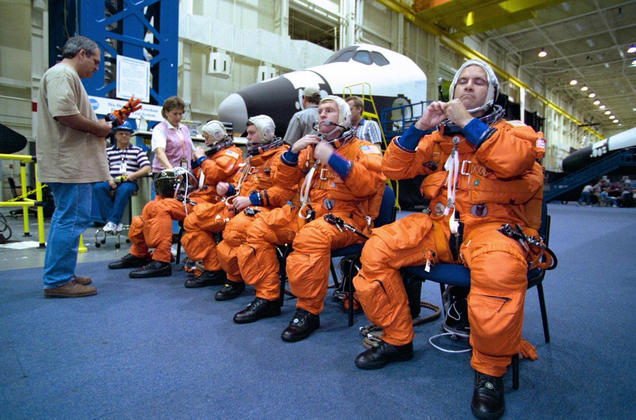 JSC2000-05551 (3 August 2000) --- Four astronauts, who comprise the core crew for STS-102,  listen to a launch and entry garment briefing by suit technician Lloyd Armintor in the Systems Integration Facility as they suit up for a contingency simulation exercise in preparation for next year's visit to the International Space Station (ISS).  From the left are astronauts James D. Wetherbee, commander; James M. Kelly, pilot; and Andrew S.W. Thomas and Paul W. Richards, both mission specialists.  The four will be joined by a cosmonaut and two other astronauts scheduled to share the &quot;up&quot; ride for a lengthy stay aboard the orbiting outpost.  Then, they will bring back a threesome made up an astronaut and two cosmonauts who will have been onboard the station since early November 2000.