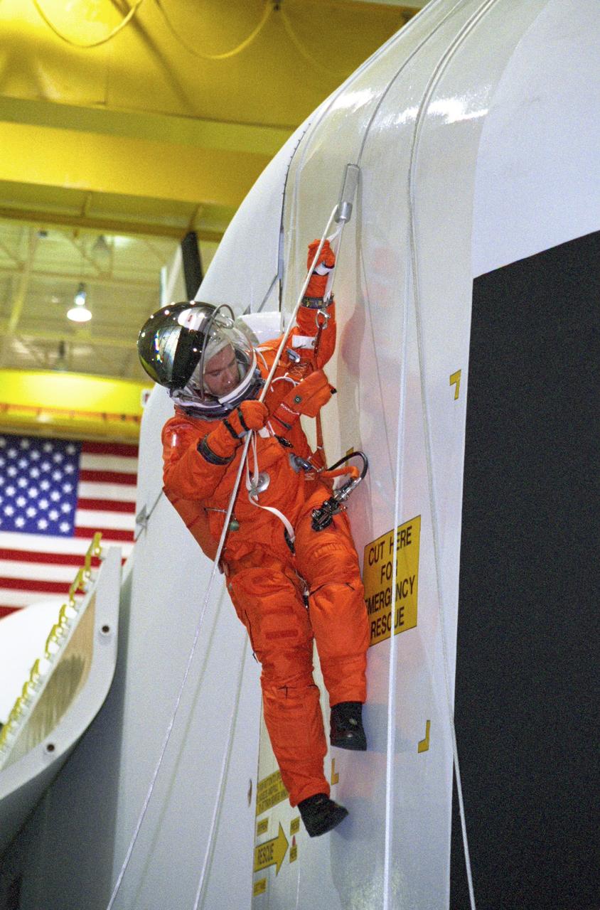 JSC2000-05553 (3 August 2000) --- Astronaut Paul W. Richards, STS-102 mission specialist, during  a session of egress training in the Johnson Space Center's Systems Integration Facility, uses a Sky-genie device to escape from a simulated shuttle in trouble.  The full fuselage trainer (FFT) is a full scale mockup of a shuttle.
