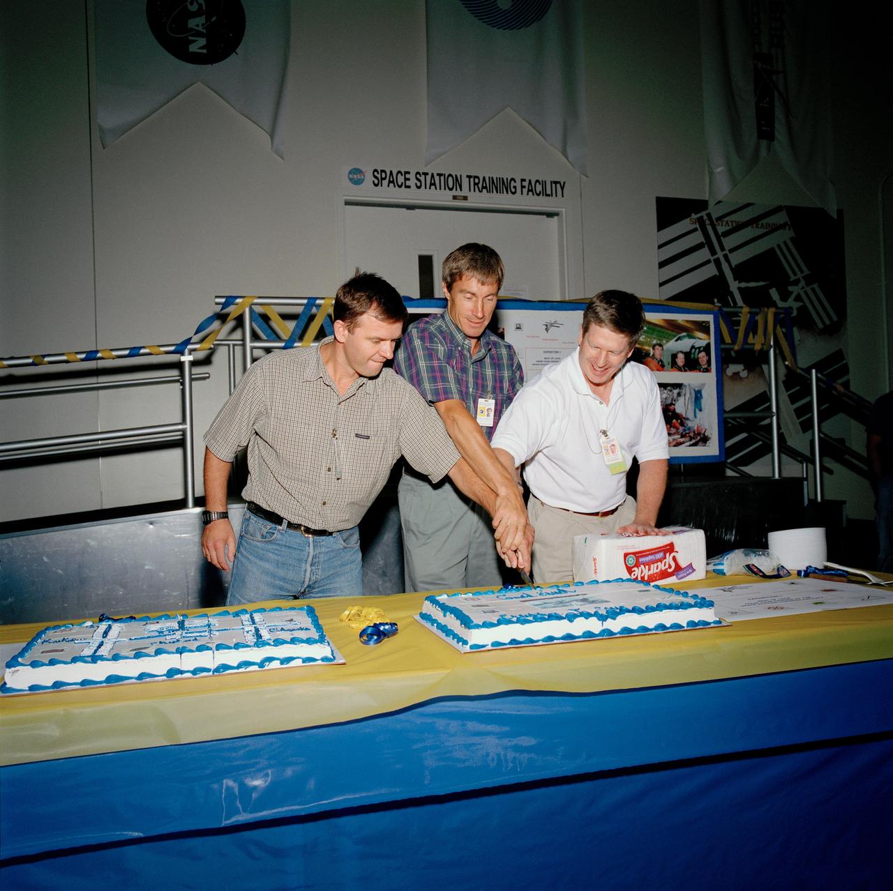 JSC2000-05569 (August 2000) --- Symbolizing the completion of its preflight training in the United States, the Expedition One crew is treated to a celebratory cake from the training team in the Mission Simulation and Training Facility at the Johnson Space Center (JSC).  The international crew, from the left,  Russian cosmonauts Yuri P. Gidzenko and Sergei K. Krikalev, along with U.S. astronaut William M. Shepherd, departed August 10 for Star City, Russia, where they will continue to train until their scheduled October 30 launch aboard a Russian Soyuz rocket. They will be the first long-duration residents of the station.
