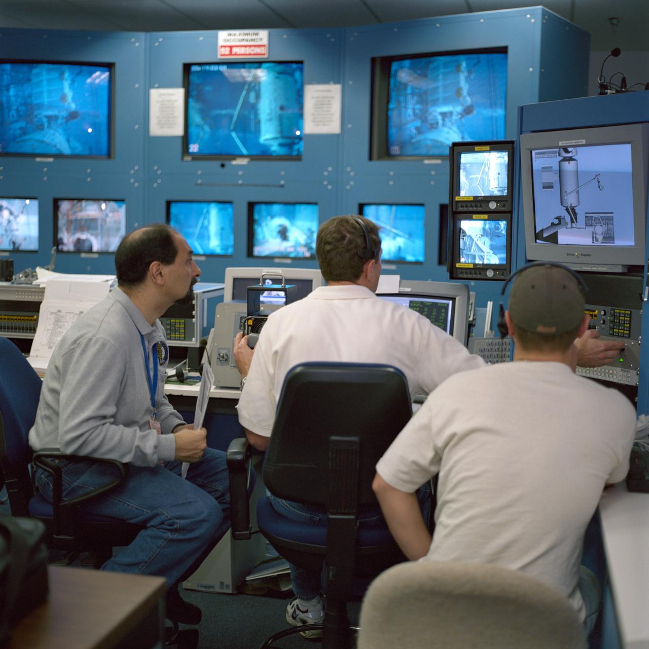 JSC2000-07406 (1 December 2000) --- Astronaut Umberto Guidoni (left), STS-100 mission specialist representing the European Space Agency (ESA), views a closed-circuit televising of an underwater space walk simulation performed by two crew mates.  The   simulation of the scheduled spring 2001 space walk took place at the Neutral Buoyancy Laboratory (NBL) at the Sonny Carter Training Facility.  Astronaut Jeffrey S. Ashby, pilot, is at center. Astronauts Scott E. Parazynski of the NASA-Johnson Space Center and Chris A. Hadfield of the Canadian Space Agency  (CSA), both  mission specialists and both equipped with training versions of the extravehicular mobility unit (EMU) space suits, were in the water at the time.