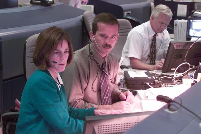 JSC2000-E-22831 (13 September 2000) ---  Astronauts Barbara R. Morgan and Chris A. Hadfield listen to downlinked audio from the Space Shuttle Atlantis at the approximate midway point of the STS-106 mission.  The two are working at the Spacecraft Communicator (CAPCOM) console in Houston's Mission Control Center (MCC).  Nearby is Bill Reeves  at the Flight Director console.