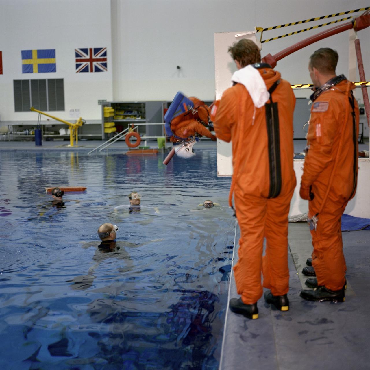 JSC2001-00002 (January 2001) --- Astronauts Michael L. Gernhardt (left), mission specialist, and Steven W. Lindsey, mission commander, look on while an unidentified member of the STS-104 crew simulates an ejection into a body of water during an emergency bailout training session for the astronauts in the Neutral Buoyancy Laboratory (NBL) near the Johnson Space Center (JSC).