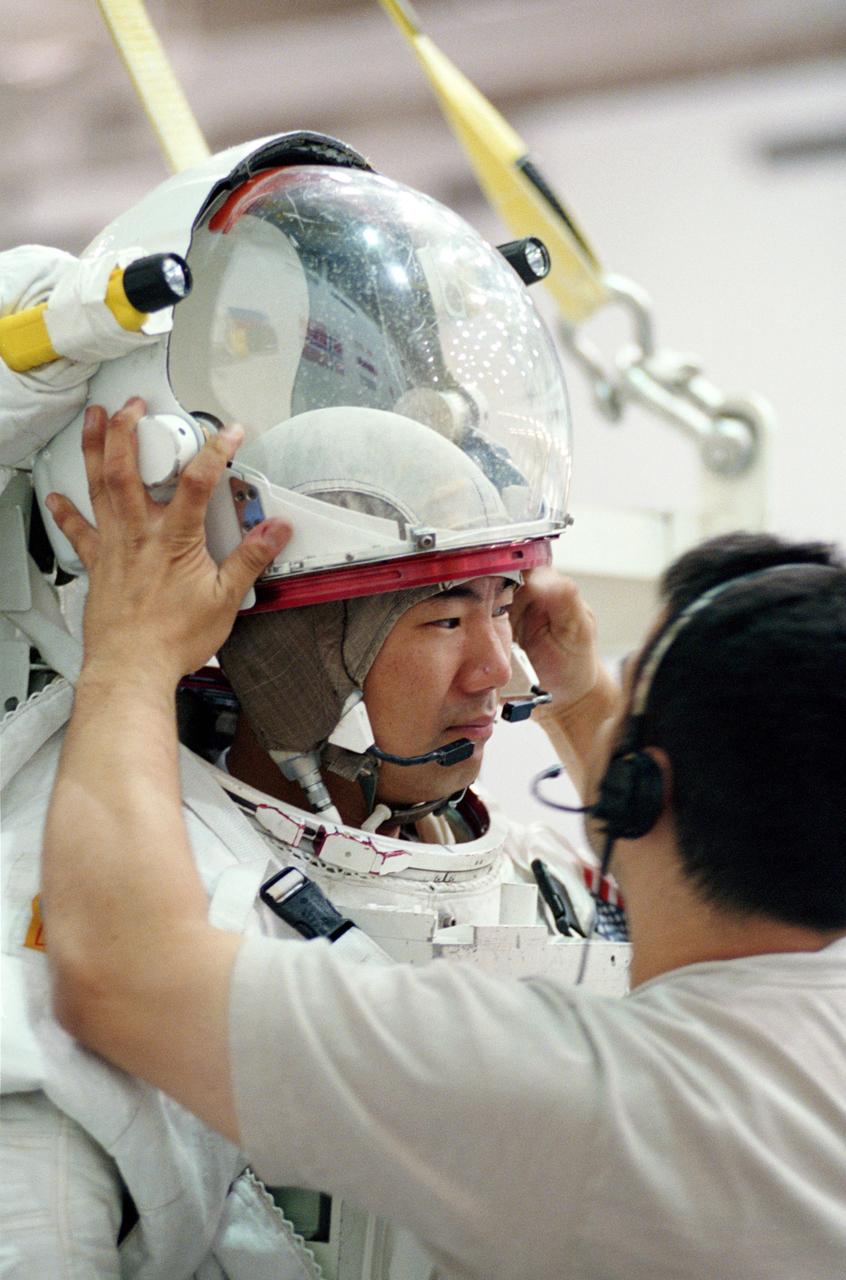 JSC2001-01438 (17 May 2001) --- Astronaut Soichi Noguchi, STS-114 mission specialist, gets help with final touches on the training version of his Extravehicular Mobility Unit (EMU) space suit prior to being submerged in the waters of the Neutral Buoyancy laboratory (NBL) at the Johnson Space Center (JSC). Noguchi represents Japan&#0146;s National Space Development Agency (NASDA).