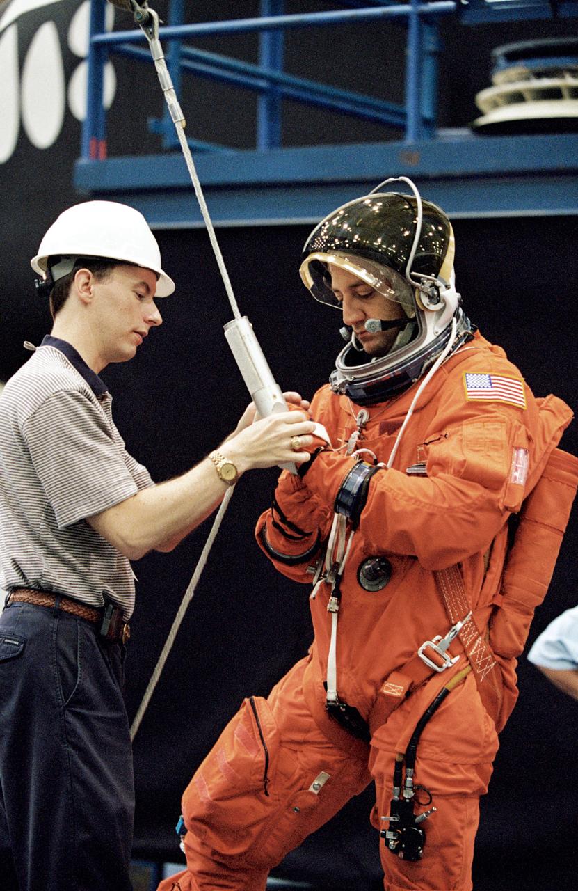 JSC2001-01543 (24 May 2001) --- Astronaut Michael J. Massimino, STS-109 mission specialist, is briefed by United Space Alliance (USA) crew trainer David Pogue on the usage of the Sky-genie device, used to lower oneself from a troubled shuttle, in a training session in the Space Vehicle Mockup Facility at the Johnson Space Center (JSC). Massimino is wearing a training version of the full-pressure launch and entry suit. STS-109 will be the 108th shuttle flight and the fourth Hubble Space Telescope (HST) servicing mission.