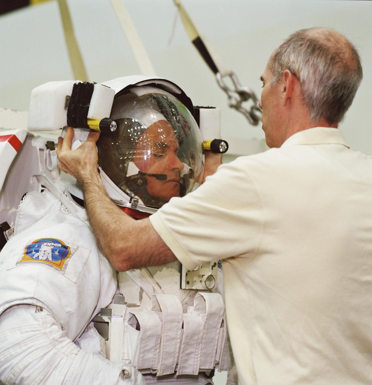 JSC2001-01614 (1 June 2001) --- Astronaut Frederick W. Sturckow, STS-105 pilot, is photographed as the final touches are made on the training version of his Extravehicular Mobility Unit (EMU) space suit prior to being submerged in the waters of the Neutral Buoyancy Laboratory (NBL) at the Johnson Space Center (JSC). Sturckow is assisted by fellow crewmember Daniel T. Barry, mission specialist.