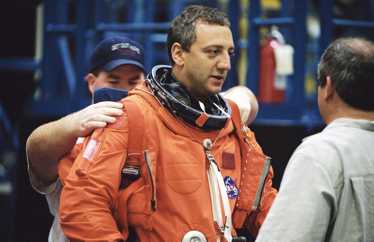 JSC2001-01875 (22 June 2001) --- Astronaut Michael J. Massimino, STS-109 mission specialist, dons a training version of the full-pressure launch and entry suit prior to a training session in one of the trainer/mockups (out of frame) in the Space Vehicle Mockup Facility at the Johnson Space Center (JSC). Massimino is assisted by Tommy McDonald and Lloyd Armintor both United Space Alliance (USA) suit technicians. STS-109 will be the 108th shuttle flight and the fourth Hubble Space Telescope (HST) servicing mission.