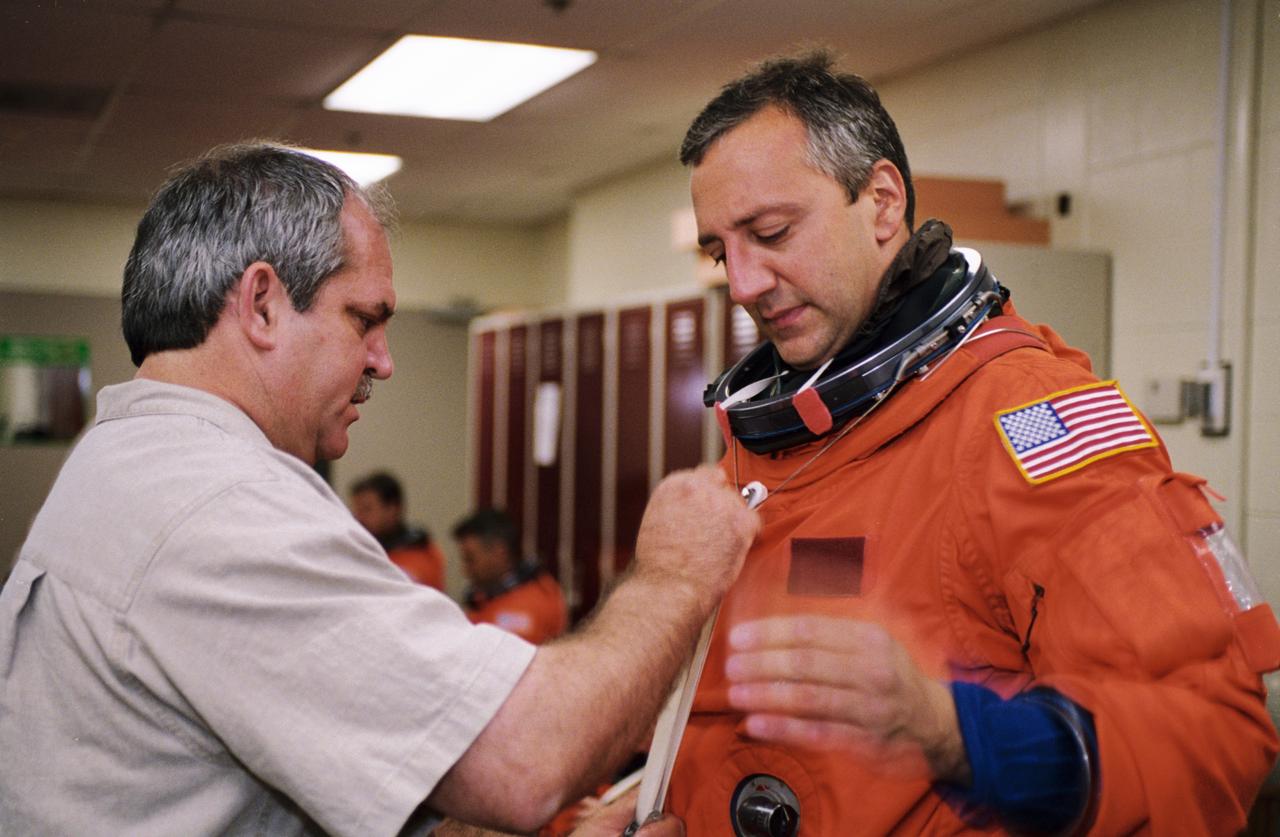 JSC2001-01889 (22 June 2001) --- Astronaut Michael J. Massimino, STS-109 mission specialist, dons a training version of the full-pressure launch and entry suit prior to a training session in one of the trainer/mockups (out of frame) in the Space Vehicle Mockup Facility at the Johnson Space Center (JSC). Massimino is assisted by United Space Alliance (USA) suit technician Lloyd Armintor. STS-109 will be the 108th shuttle flight and the fourth Hubble Space Telescope (HST) servicing mission.