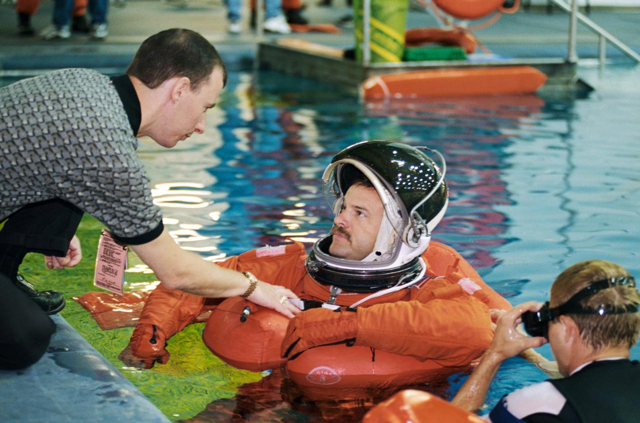 JSC2001-01921 (12 July 2001) --- Astronaut Scott D. Altman, STS-109 mission commander, is assisted by United Space Alliance (USA) crew trainer David Pogue and a diver during an emergency bailout training session in the Neutral Buoyancy Laboratory (NBL) near the Johnson Space Center (JSC). STS-109 will be the 108th shuttle flight and the fourth Hubble Space Telescope (HST) servicing mission.