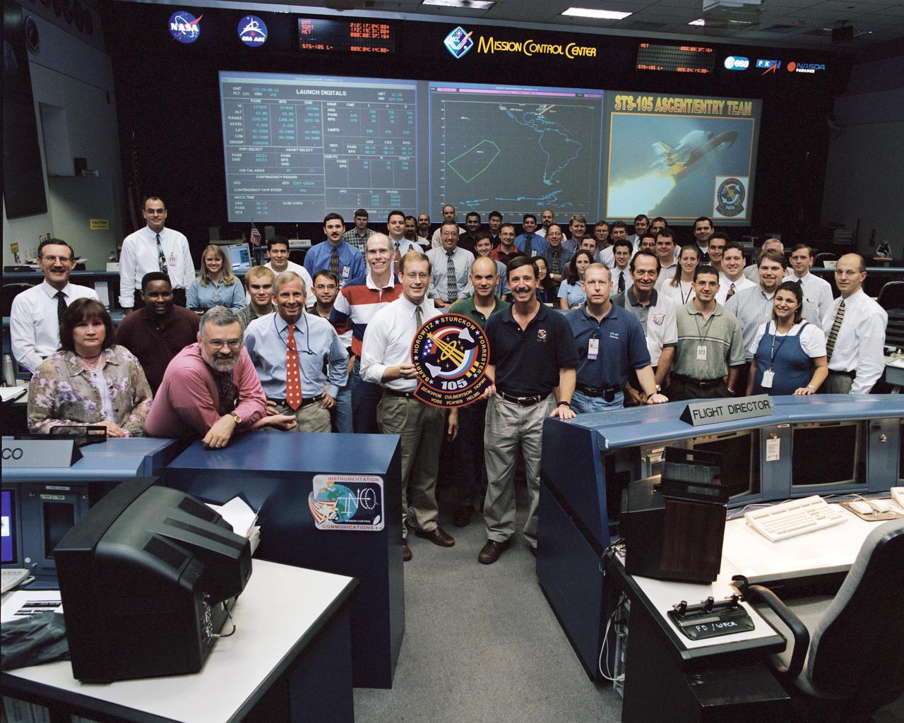 JSC2001-02115 (31 July 2001) --- The flight controllers for the Ascent/Entry shift for the upcoming STS-105 mission pose with the assigned astronaut crew for a team portrait in the Shuttle Flight Control Room (WFCR) of Houston's Mission Control Center (MCC). Flight director John Shannon (left center) and STS-105 commander Scott J. Horowitz hold the mission logo. Also pictured on the front row are spacecraft communicator Kenneth D. Cockrell and STS-105 crew members Daniel T. Barry, Frederick W. (Rick) Sturckow and Patrick G. Forrester. The team had been participating in an integrated simulation for the scheduled August mission.