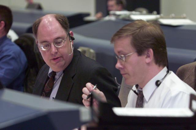 JSC2001-E-06202 (8 March 2001) --- At their console in Houston's Mission Control Center, flight directors Wayne Hale (left) and John Shannon discuss a mission detail while awaiting launch several hundred miles away in Florida.  Hale is ascent director and Shannon is lead and Orbit 1 director