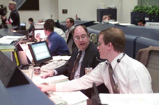 JSC2001-E-06214 (8 March 2001) --- At their console in Houston's Mission Control Center, flight directors Wayne Hale (left) and John Shannon discuss a mission detail while awaiting launch several hundred miles away in Florida.  Hale is ascent director and Shannon is lead and Orbit 1 director.