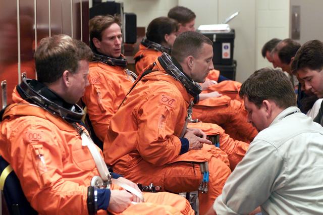 JSC2001-E-06407 (27 February 2001) --- Astronauts (from left foreground) Steven W. Lindsey, commander; Charles O. Hobaugh, pilot; Michael L. Gernhardt, Janet L. Kavandi, and James F. Reilly, all mission specialists, don training versions of the full-pressure launch and entry suit prior to a training session in one of the trainer/mockups (out of frame) in the Johnson Space Center’s Systems Integration Facility. The astronauts are assisted by suit technicians (from right foreground) Len Groce, Mike Thompson, Drew Billingsley and Jim Cheatham. The STS-104 mission to the International Space Station (ISS) represents the Space Shuttle Atlantis' first flight using a new engine and is targeted for a liftoff no earlier than June 14, 2001.